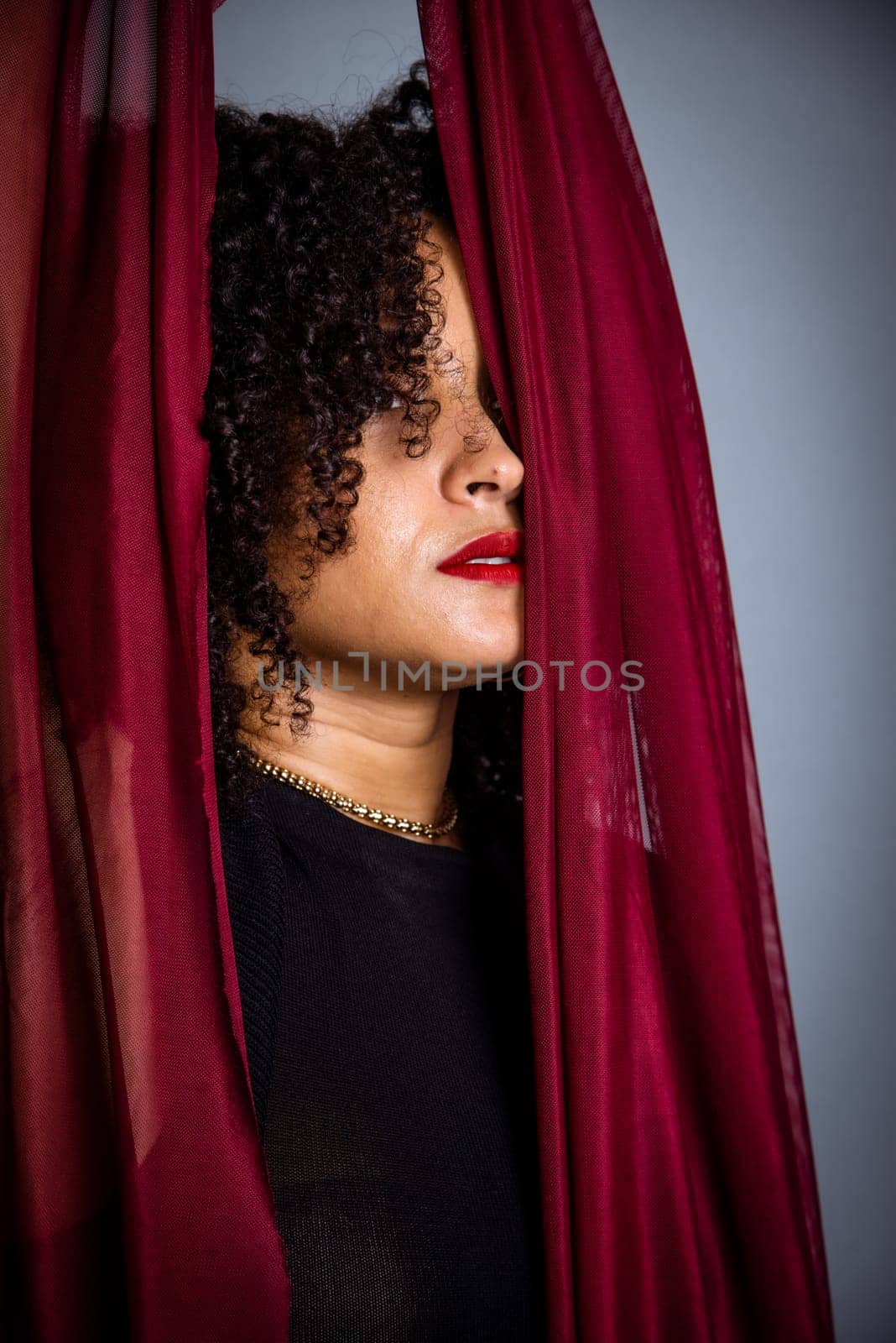 Beautiful young woman with red cloth suspended around her body. studio portrait