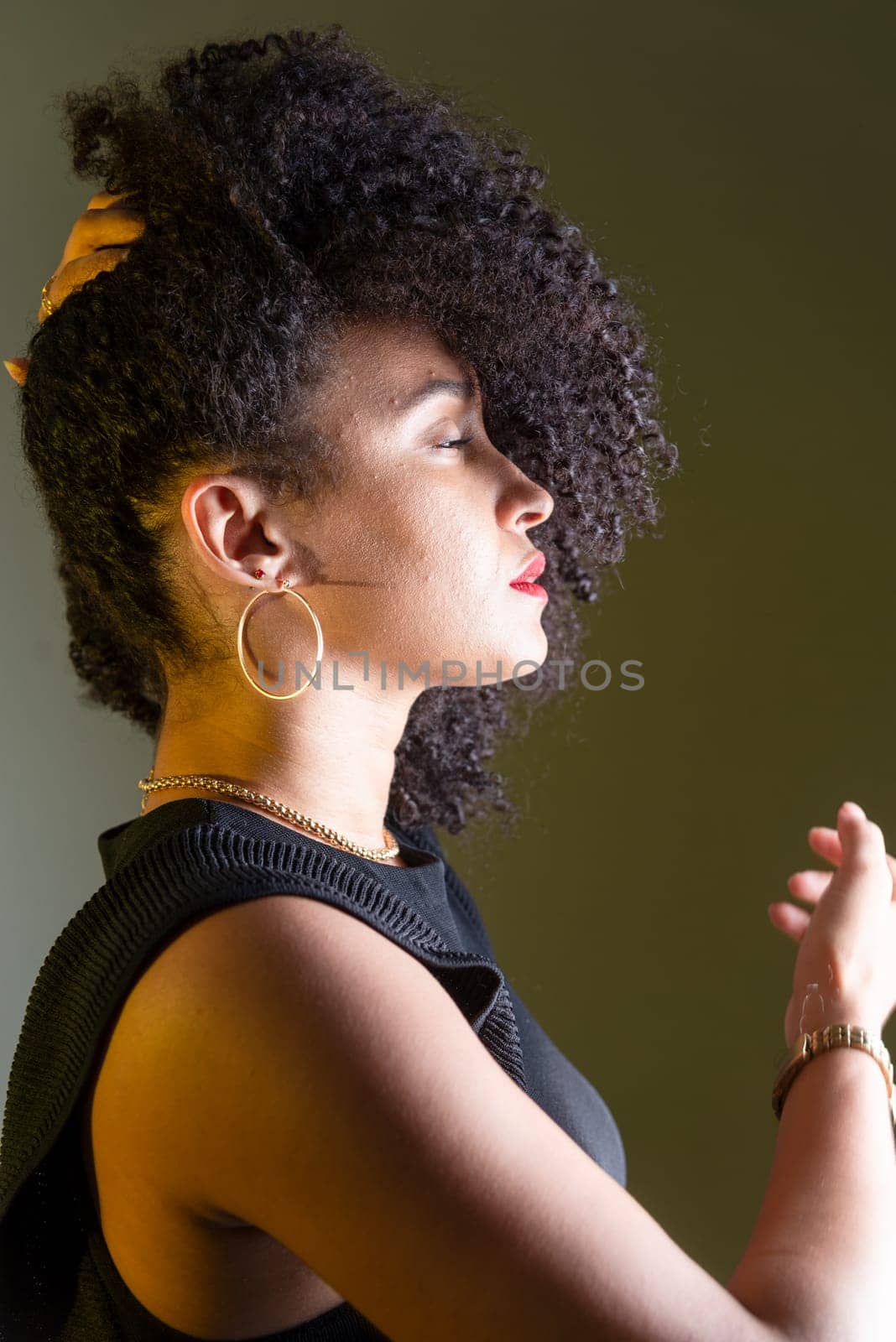 Beautiful young woman in profile wearing black clothing, with hair in her face. Studio portrait.