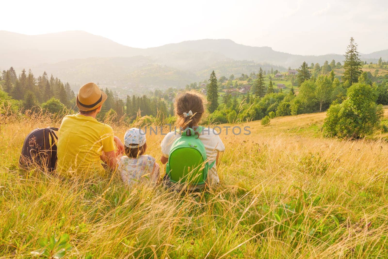 Green weekend family looking at mountain travel nature. Happy young family sitting back view mountain family nature vacation green travel together nature child mountain kid parents child landscape kid
