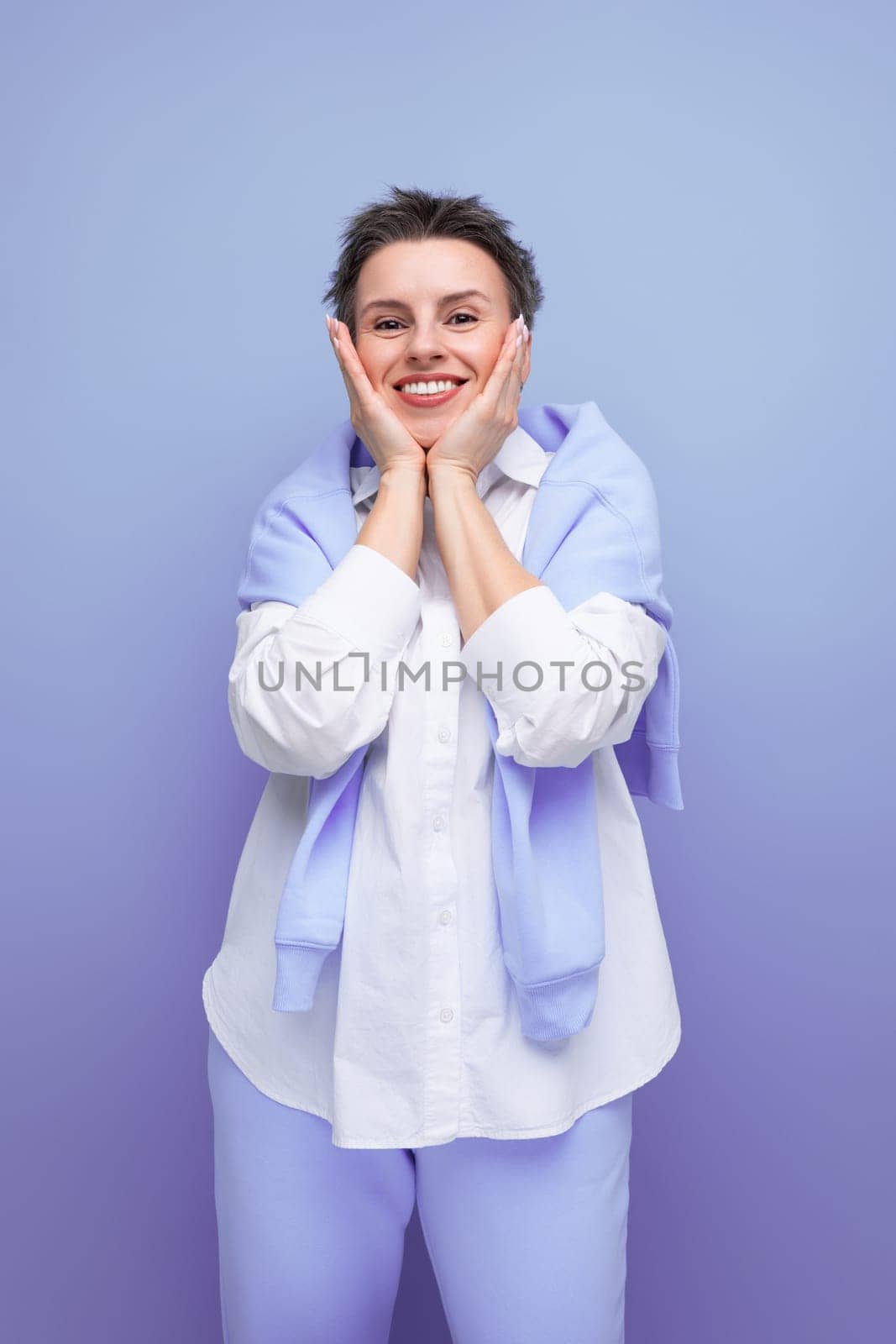 vertical photo of a stylish fashionable young lady with tousled hair in a white shirt in an informal setting.