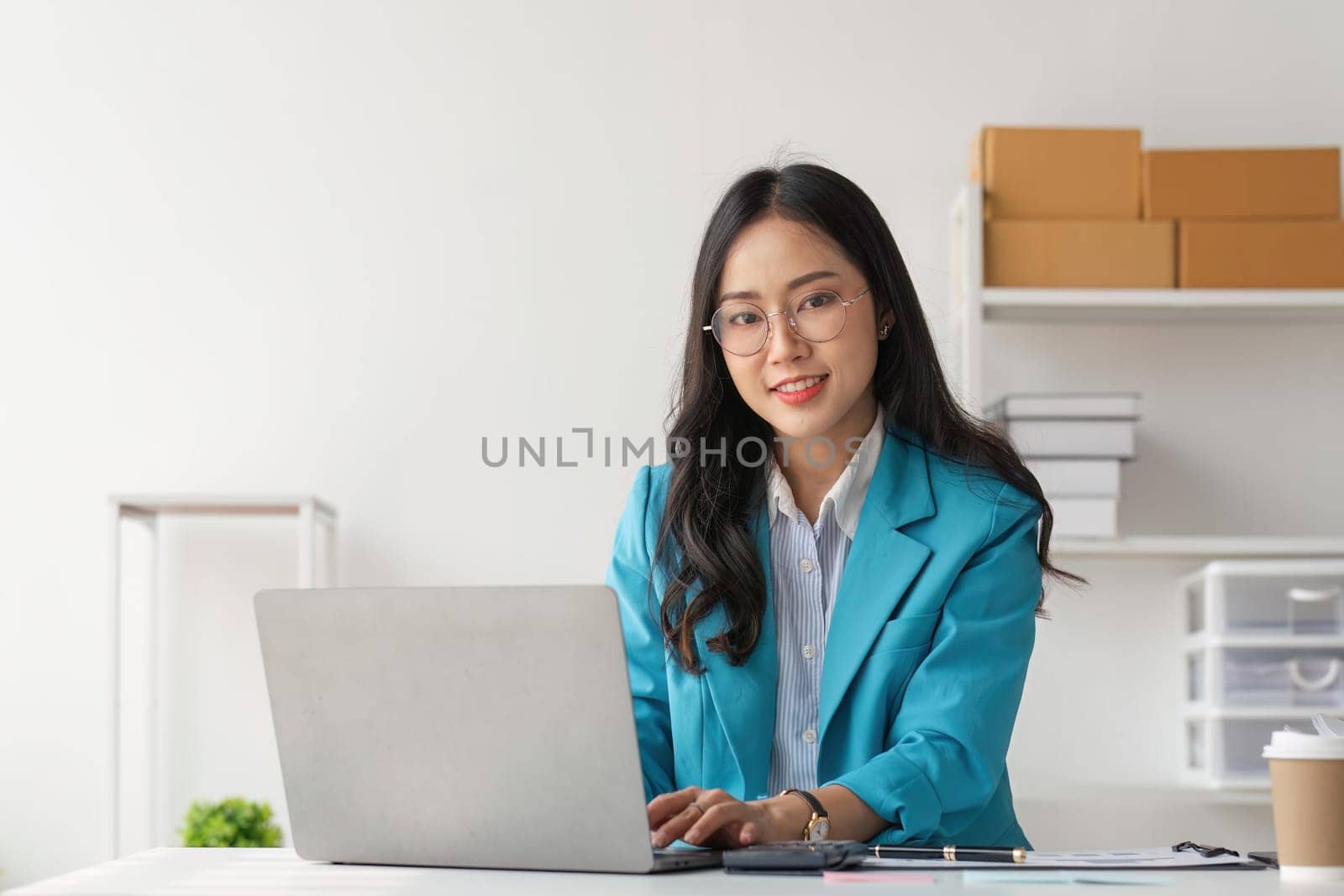 Young business woman working on laptop in office.