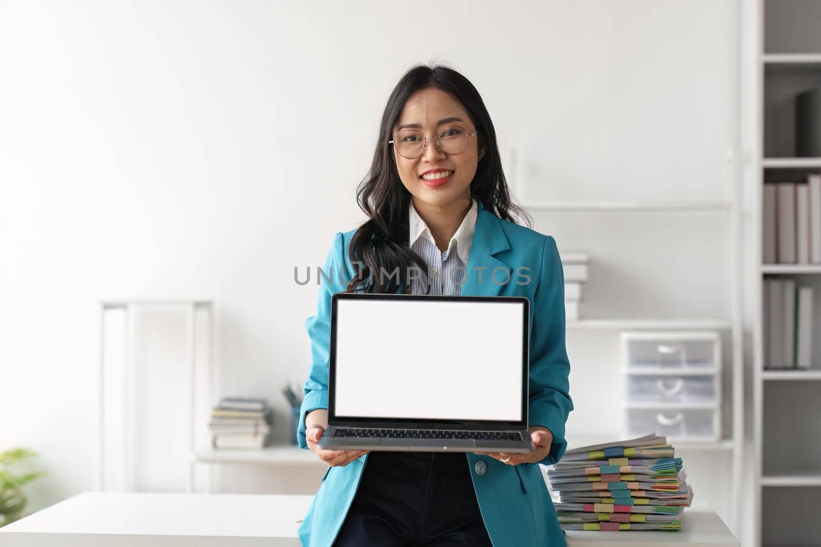 beautiful asian business girl image holding a laptop with blank white desktop screen at office.