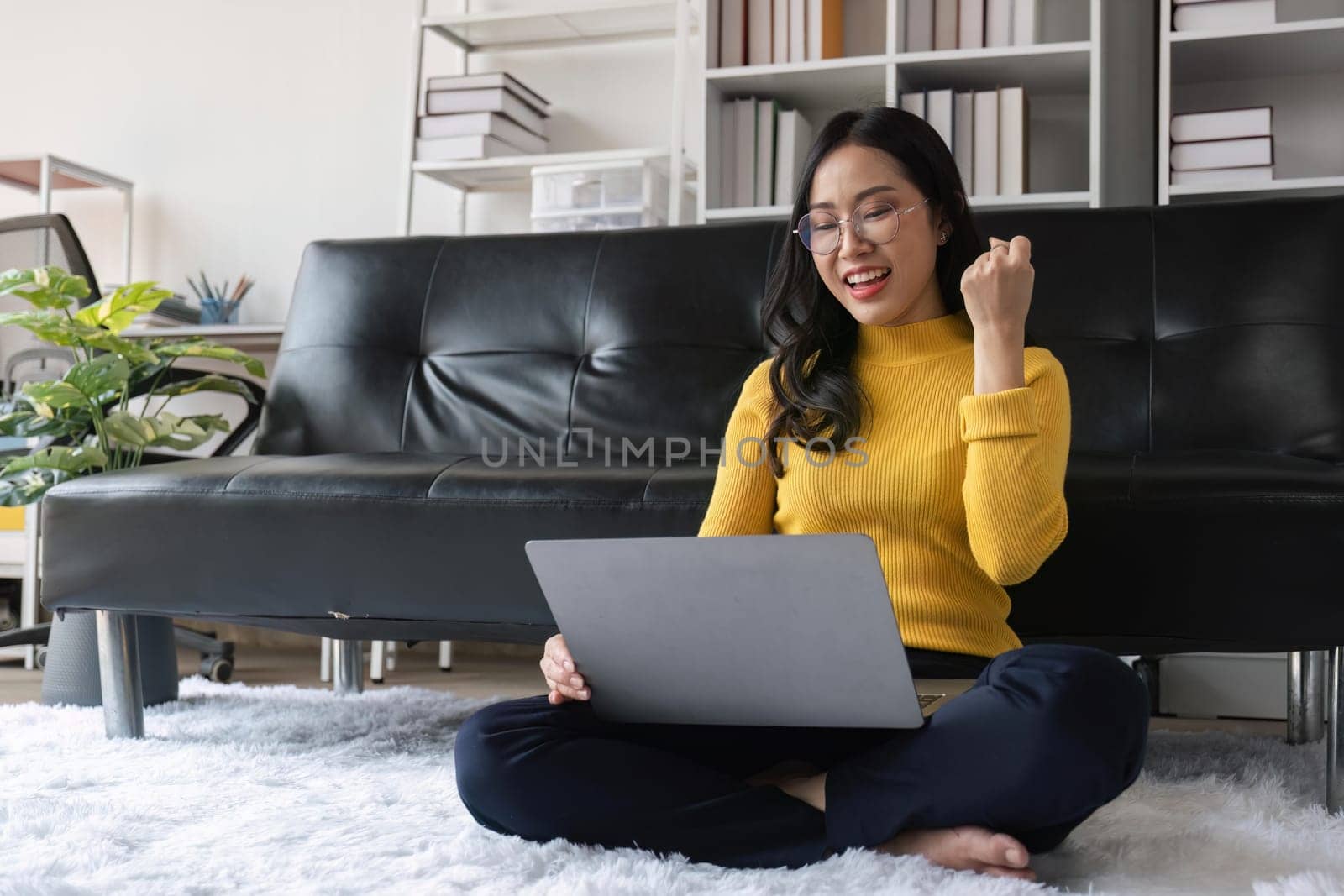 euphoric young asian woman celebrating winning or getting ecommerce shopping offer on computer laptop. Excited happy girl winner looking at laptop celebrating success.