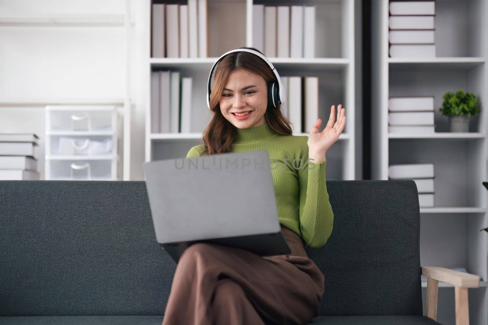 Portrait of young woman with using her laptop compute on video call with family or friends happily by nateemee