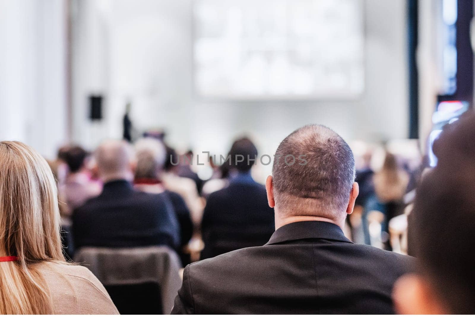 Speaker giving a talk in conference hall at business event. Rear view of unrecognizable people in audience at the conference hall. Business and entrepreneurship concept. by kasto