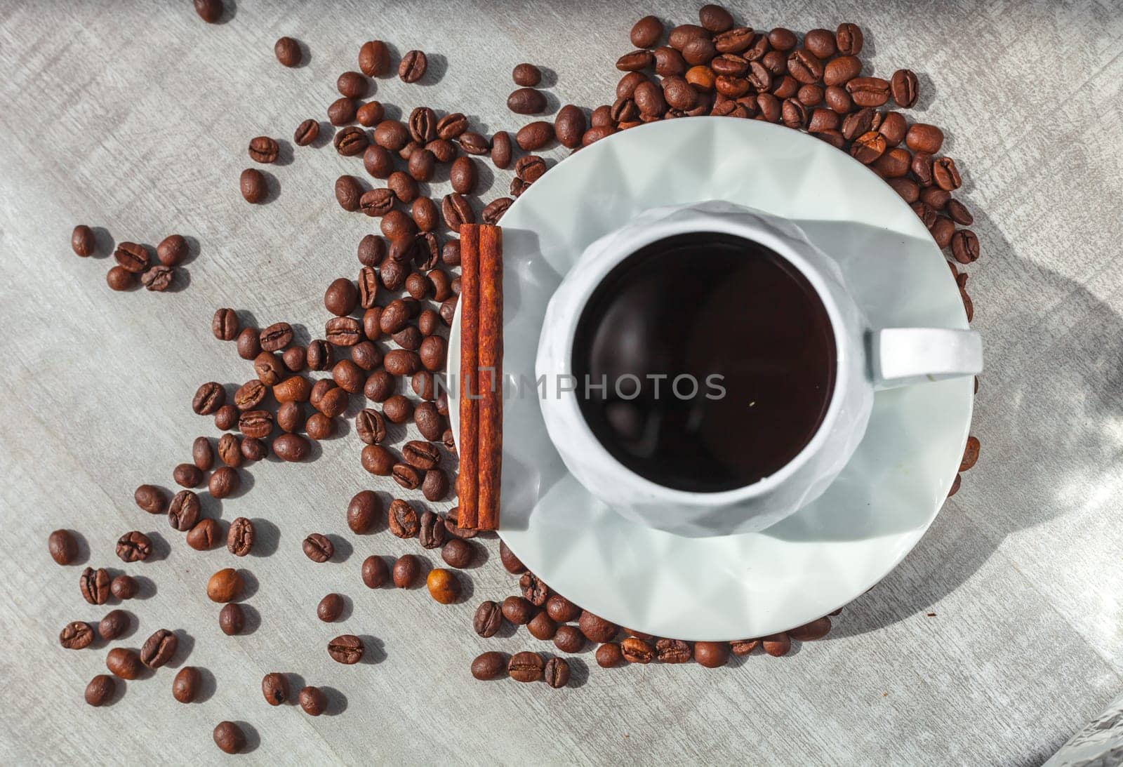 ccup of coffee on the plate with cinnamon on table and coffee beans around