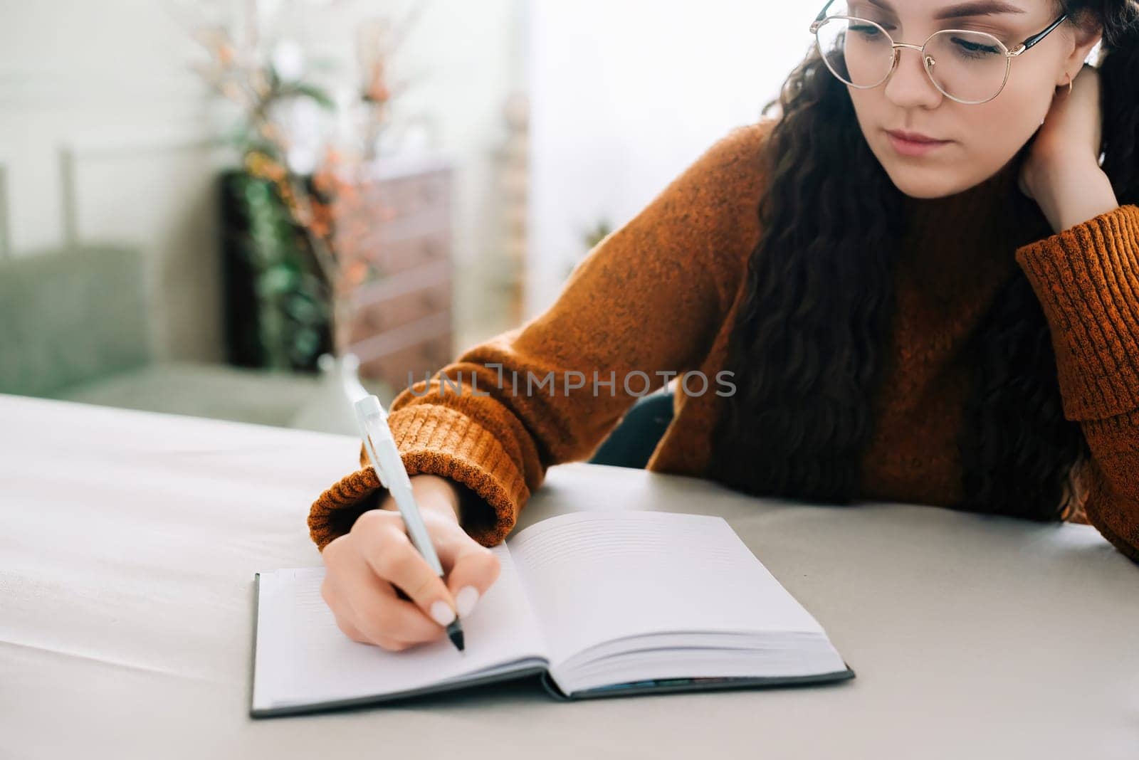 Woman writing in copybook. Business woman or young female student holding pen in hand writing in paper notebook journal, taking notes studying, doing homework, making checklist. Close up view.
