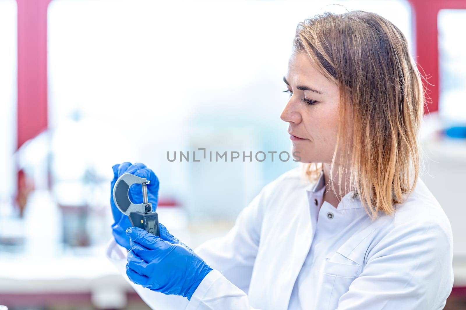 accurate mechanical measurement of the sample in a research laboratory. young caucasian woman scientist conducts research by Edophoto