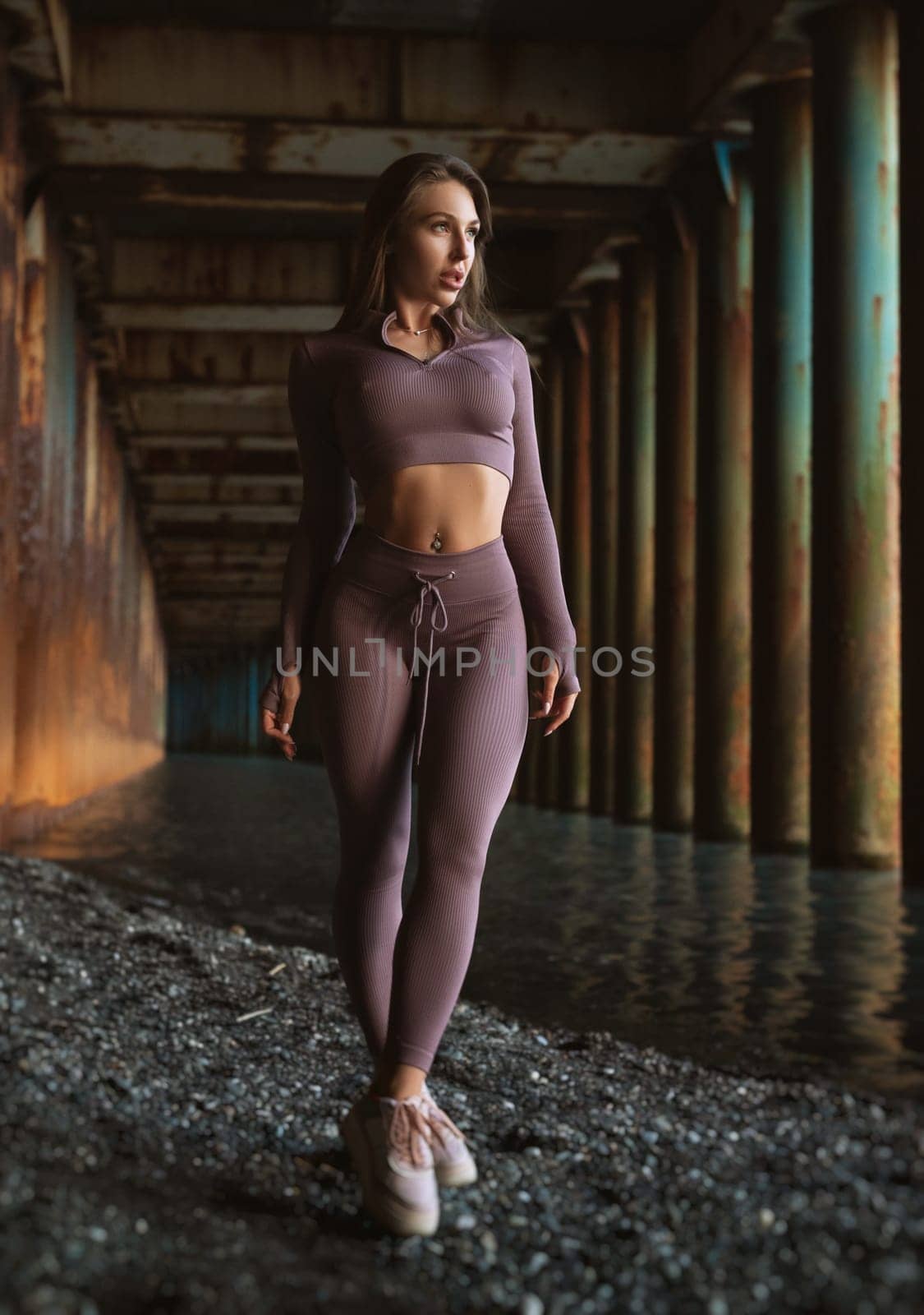 sexy athletic girl in a tight tracksuit poses sexy on background grunge by Rotozey