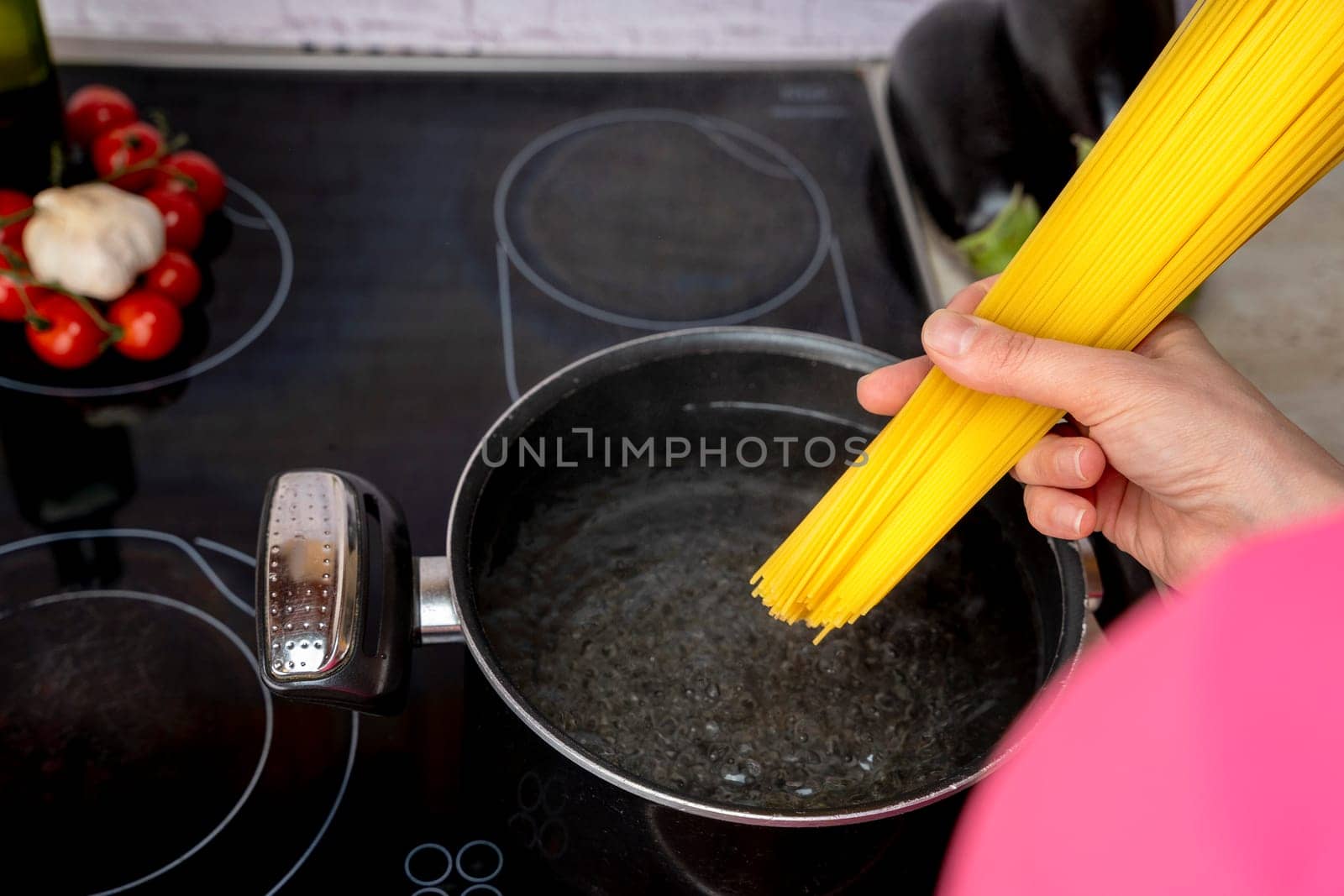 cook's hand drops the spaghetti into a saucepan of boiling wate by audiznam2609