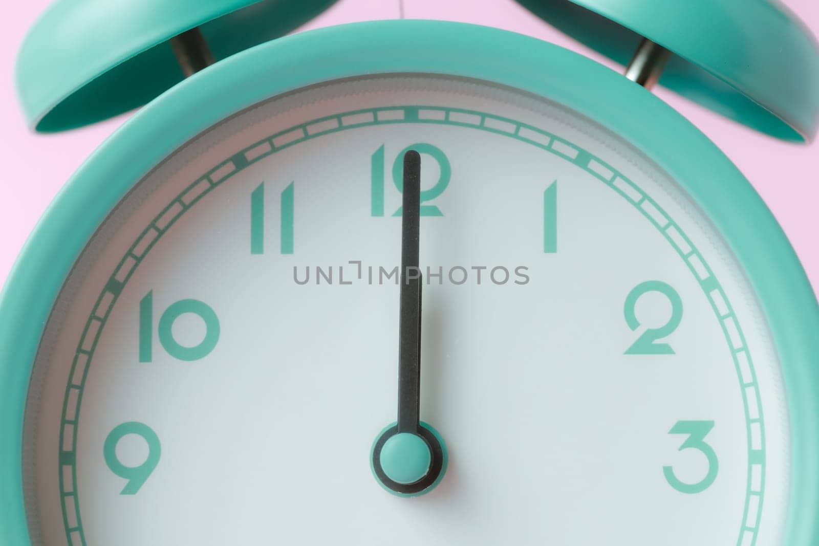 An enlarged image of a bell alarm clock with the hands pointing to noon the idea of time management.