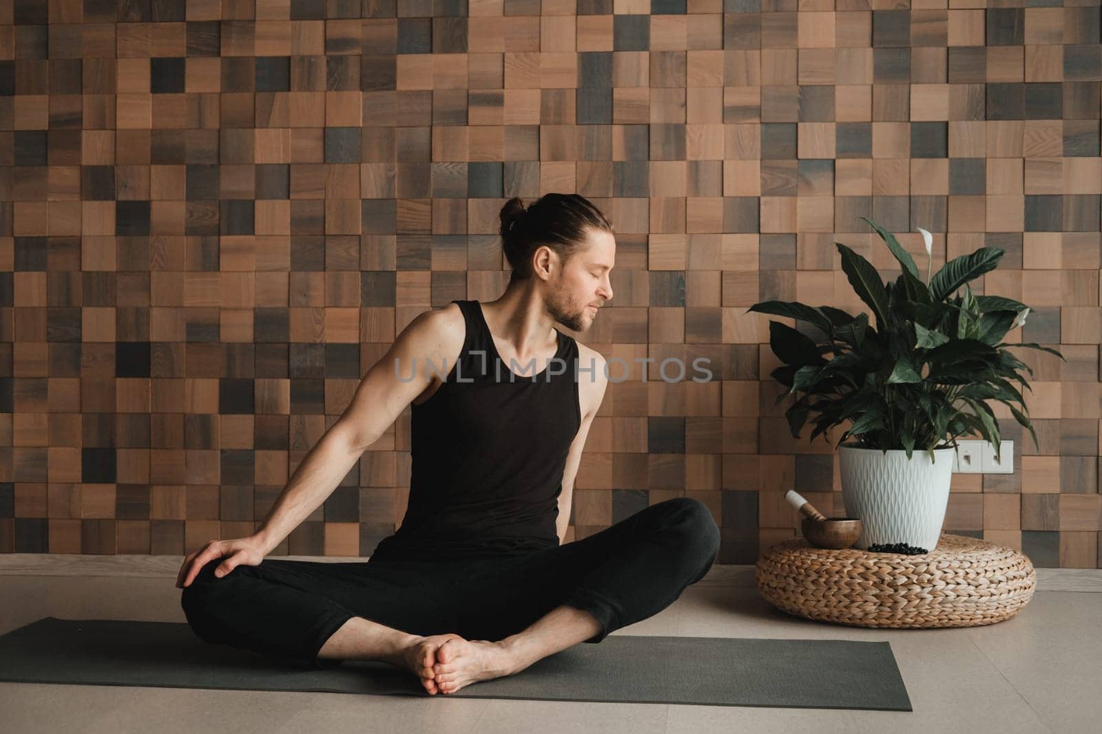 A man performing gymnastic exercises on a yoga mat at home.