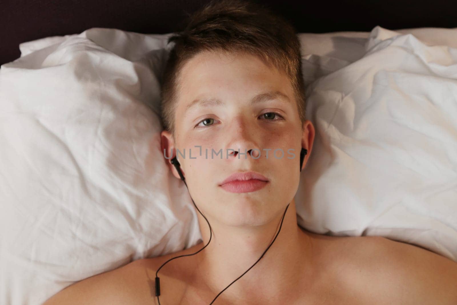 Head of a boy in headphones on a white pillow.