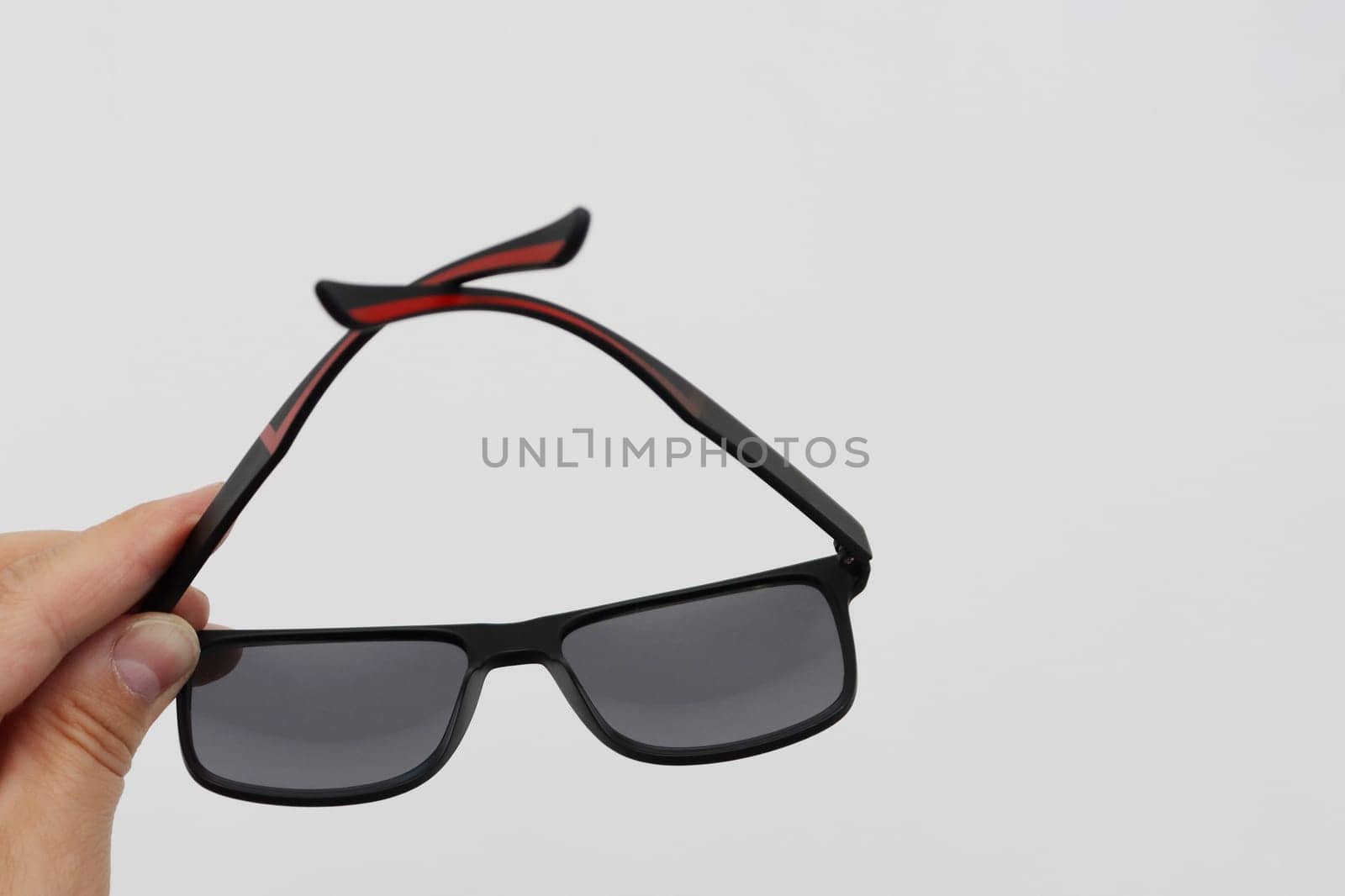 Black stylish sunglasses in hand on a gray background. Fashion summer concept. Copy space.