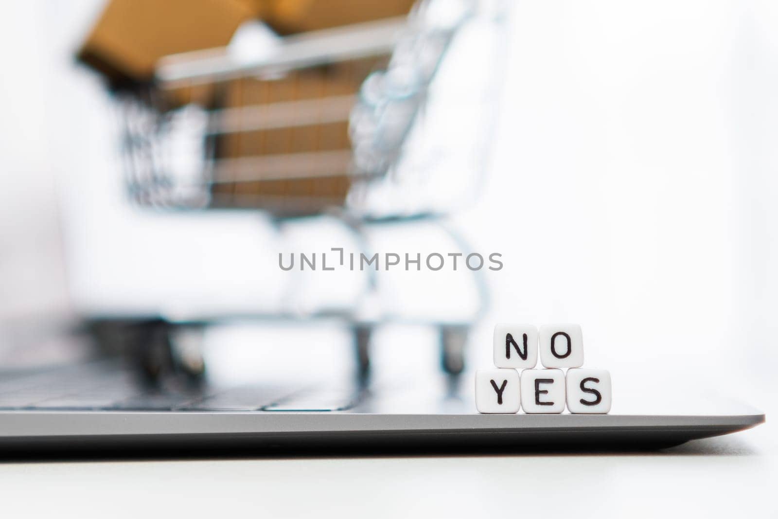 Yes or no words on cubes with a toy shopping cart and cardboard boxes in the background