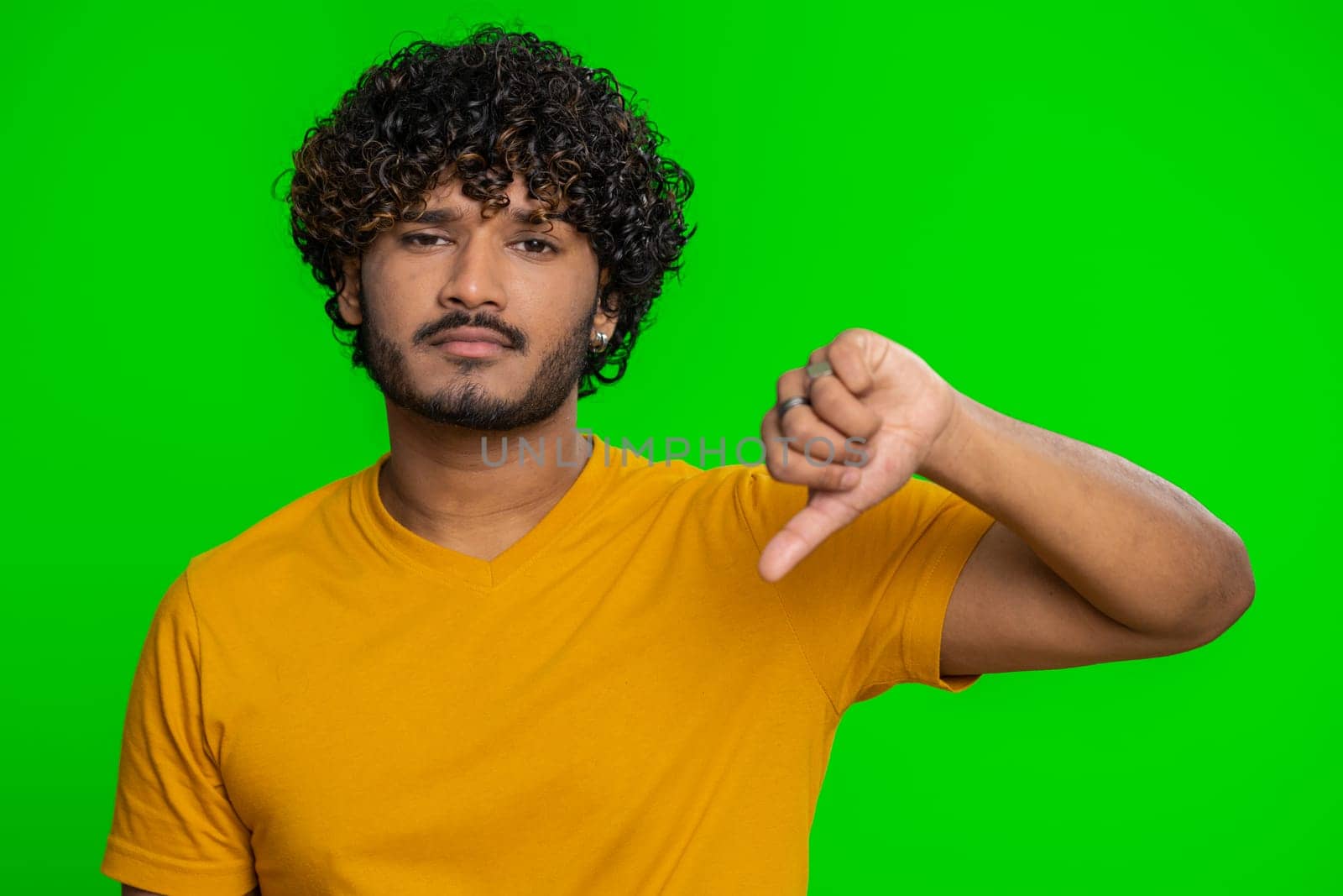 Dislike. Upset unhappy indian man in shirt showing thumbs down sign gesture, expressing discontent, disapproval, dissatisfied, dislike. Handsome young guy. Indoors studio shot on chroma key background