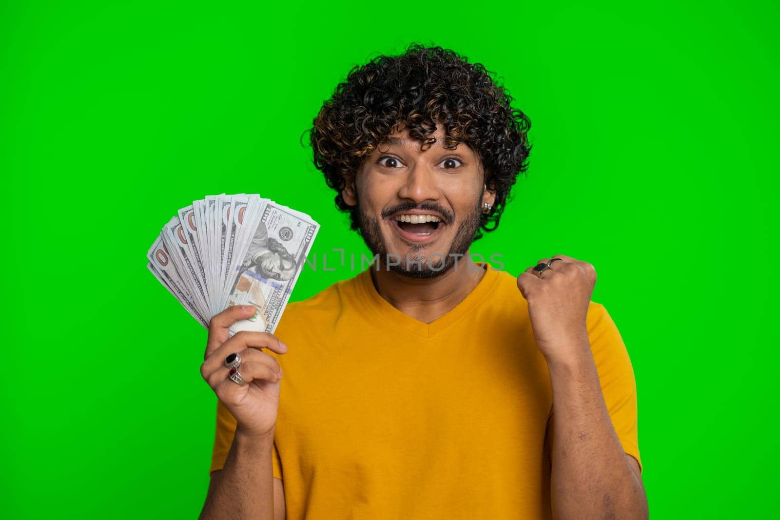 Rich pleased boss hindu man waving money dollar cash banknotes bills like a fan, success business career, lottery winner, big income, wealth. Handsome indian guy isolated on chroma key background