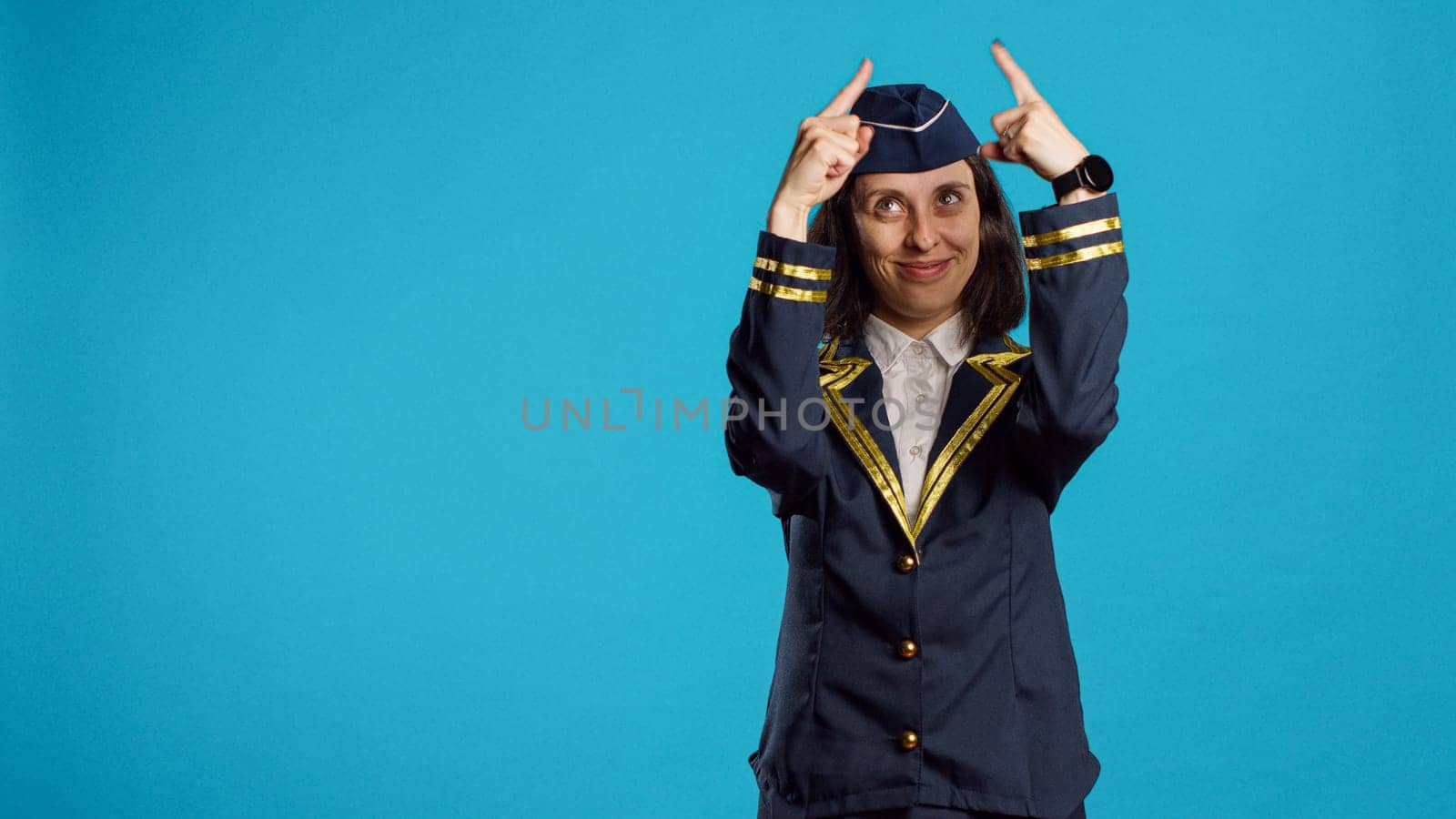 Smilign airliner doing heart shaped sign with hands, showing romantic feelings and love on vday. Young person working as stewardess feeling sweet and cute with beautiful gesture.