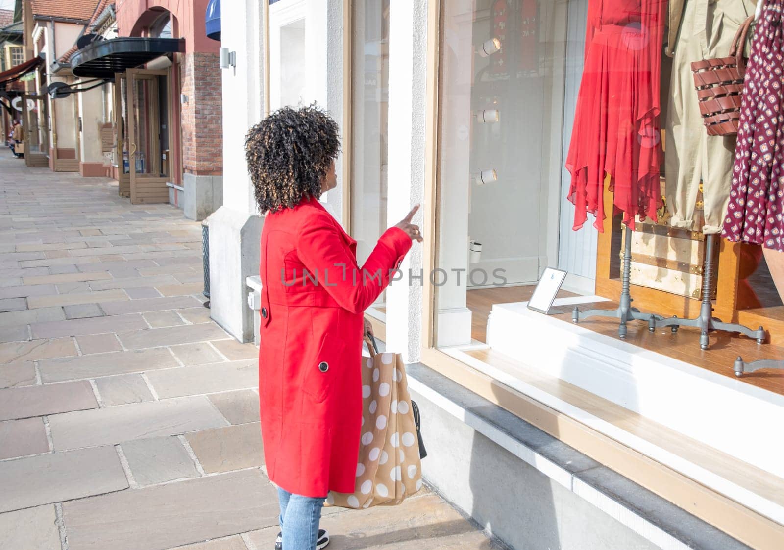 Happy confident smiling curvy african american woman with shopping bags standing on city street near shop windows. High quality photo