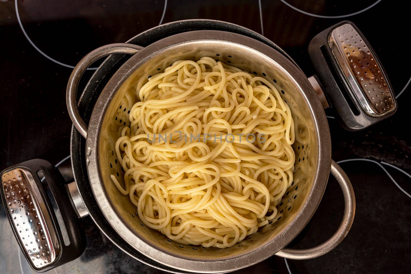 we cook ourselves. cooked ready-made spaghetti on the stove. boiled ready-made spaghetti toss in a colander. pot with spaghetti . cooking spaghetti. homemade Italian-style dinner. Pasta cooking. view from above