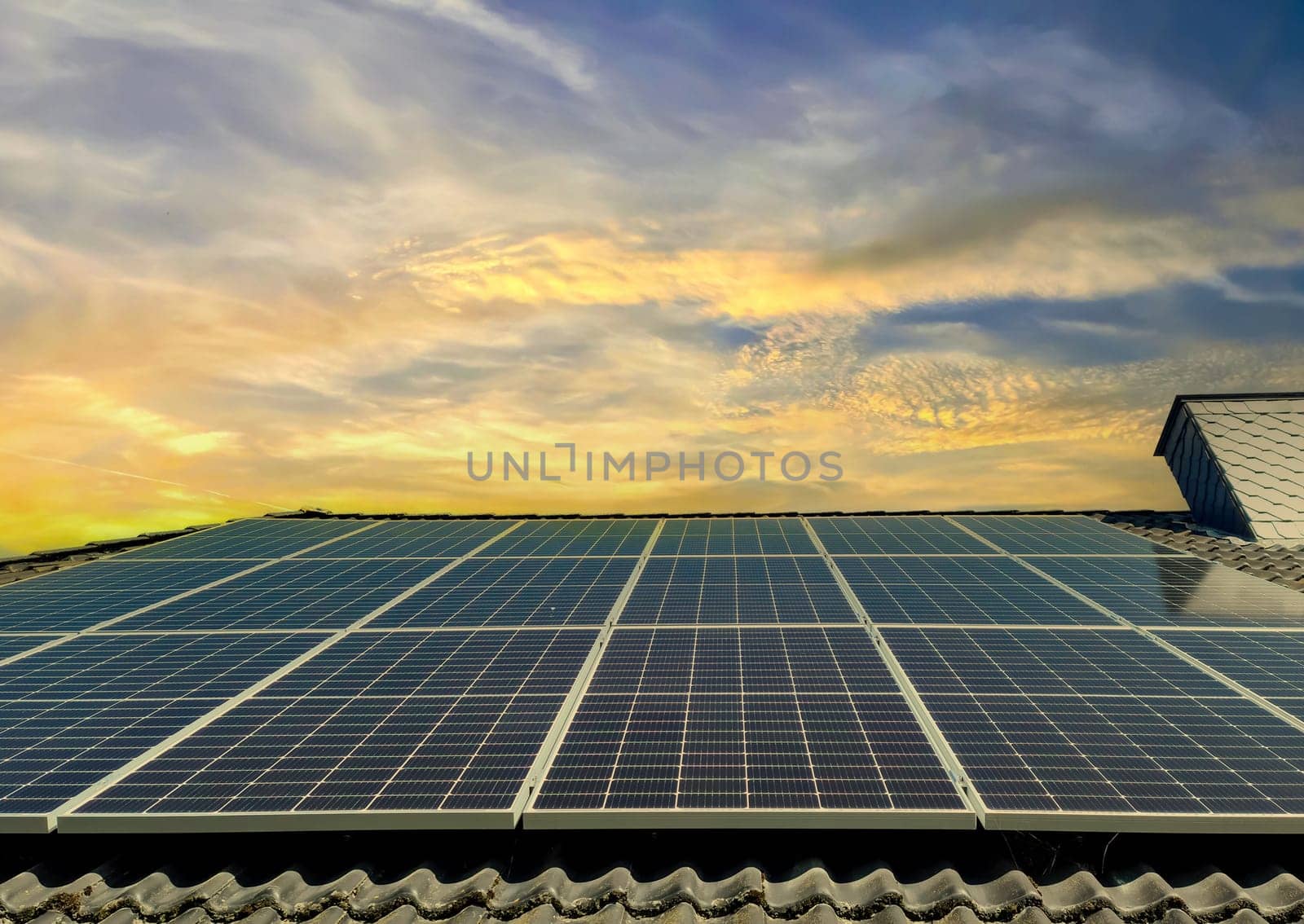 Solar panels producing clean energy on a roof of a residential house during sunset. by MP_foto71