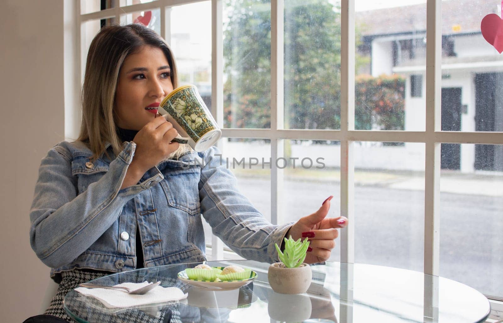 pretty woman having a coffee inside a cafeteria while looking at the street through a window. High quality photo