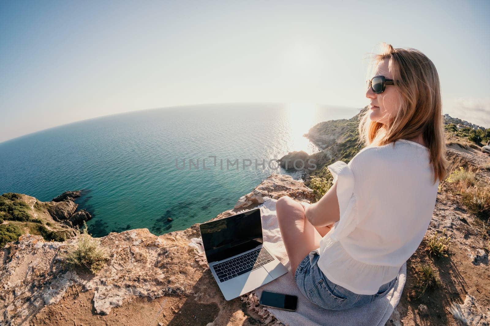 Woman sea laptop. Business woman in yellow hat working on laptop by sea. Close up on hands of pretty lady typing on computer outdoors summer day. Freelance, digital nomad, travel and holidays concept.