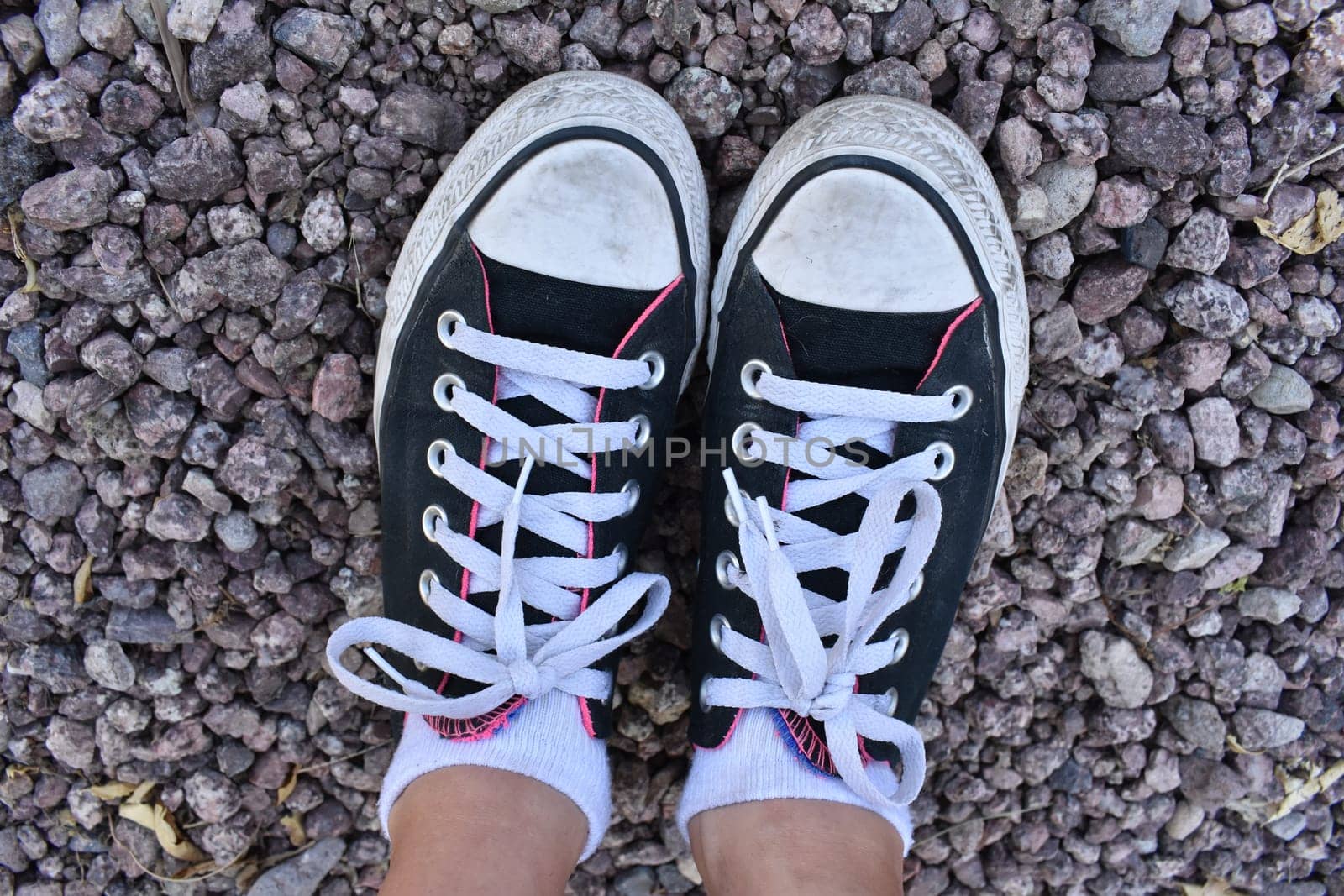 Black and White Sneakers on Rocky Ground . High quality photo