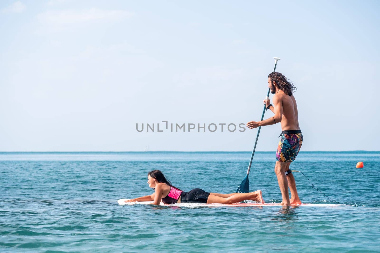 Silhouette of woman standing, surfing on SUP board, confident paddling through water surface. Idyllic sunset or sunrise. Sports active lifestyle at sea or river.