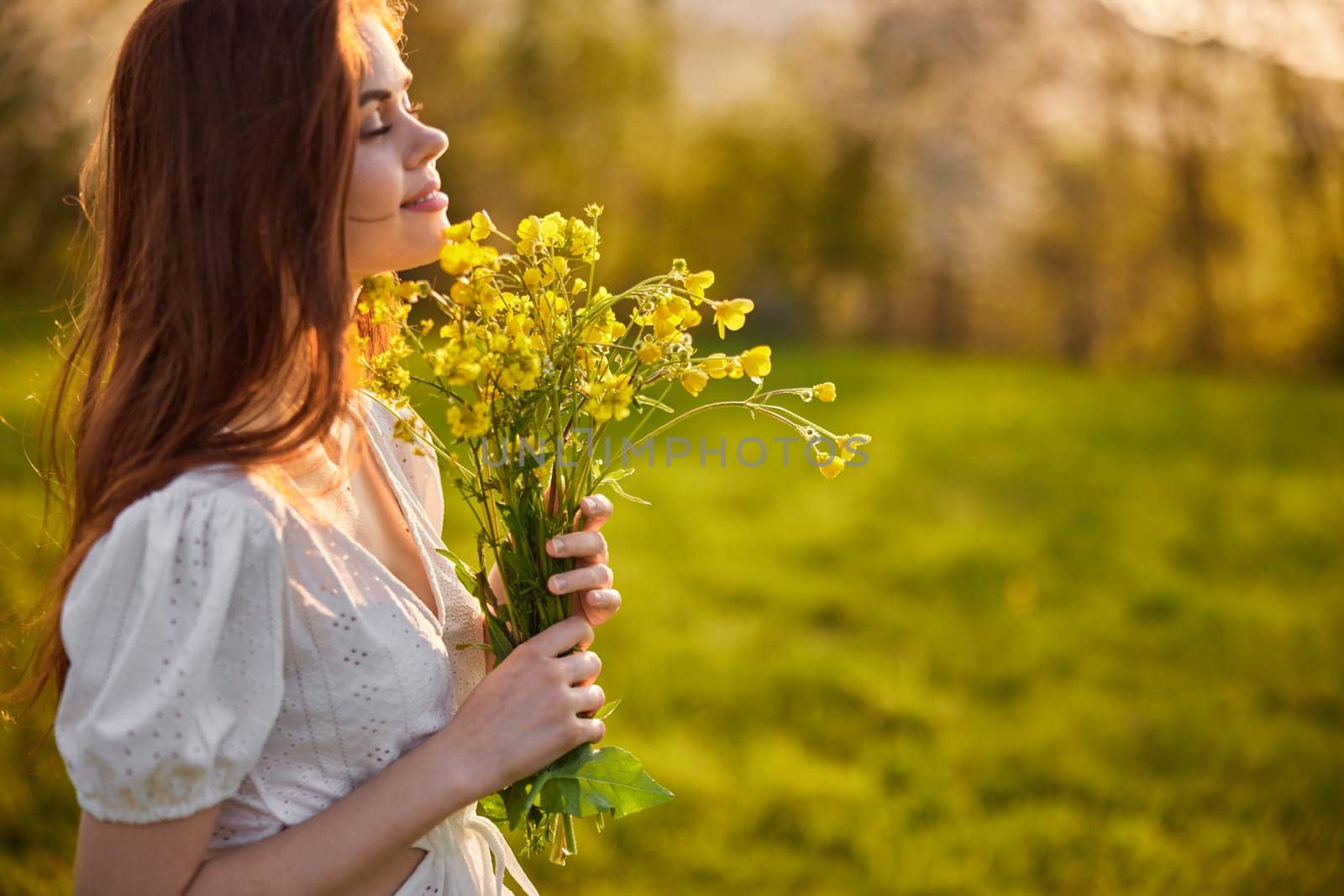 portrait of a woman with a bouquet of wild flowers in the rays of the setting sun in a field by Vichizh