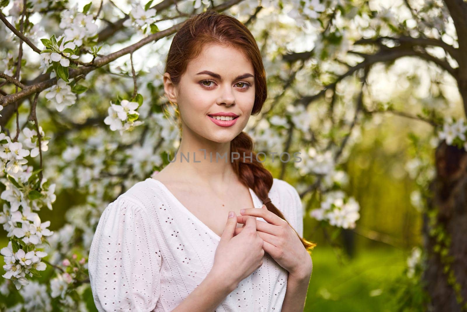 portrait of a lovely woman standing by a flowering tree with her arms folded across her chest by Vichizh