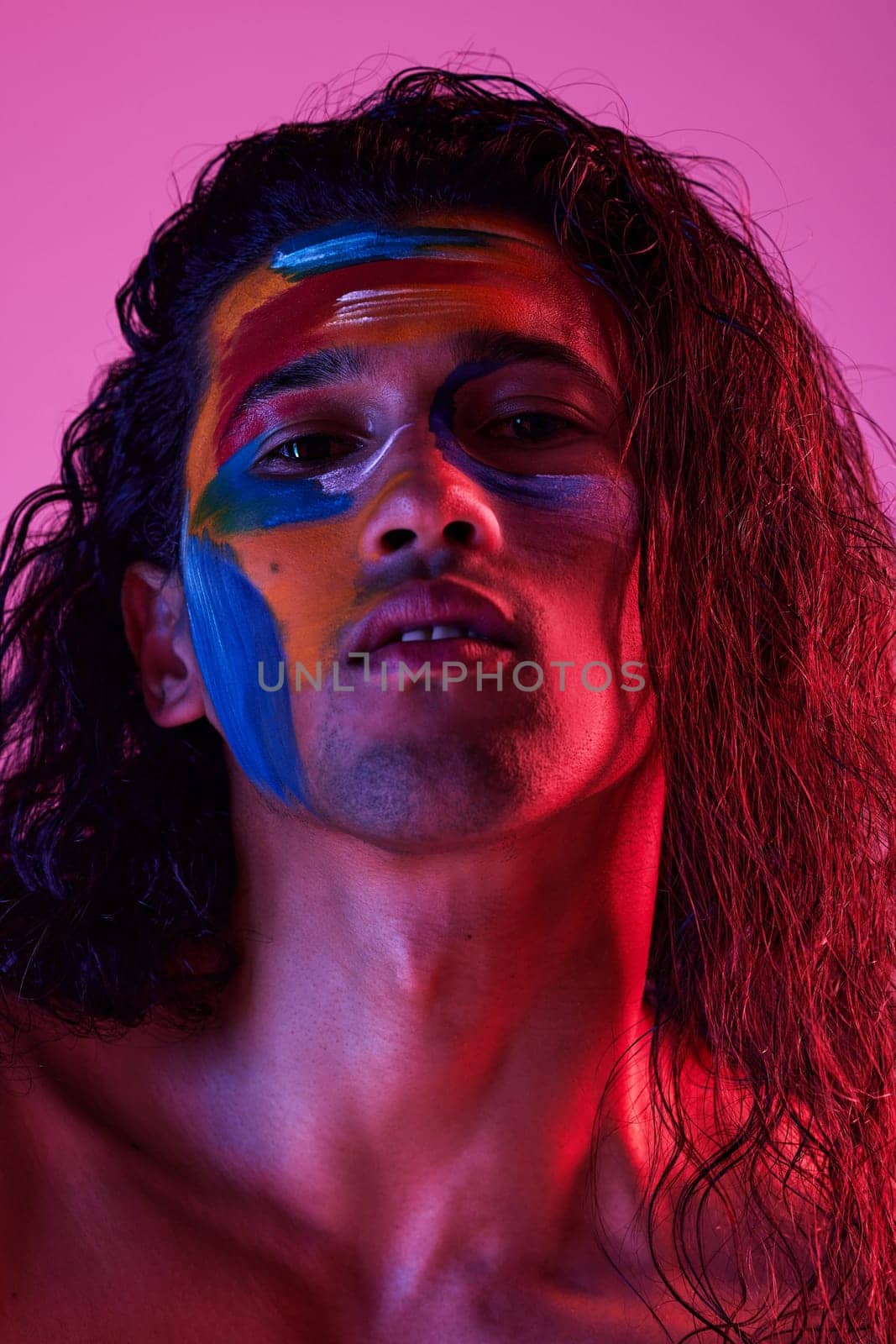 Beauty, cosmetics and portrait of man with paint for creative art, makeup and glow on studio background. Neon lighting, skincare and color on face of male model for fantasy, abstract and aesthetic.