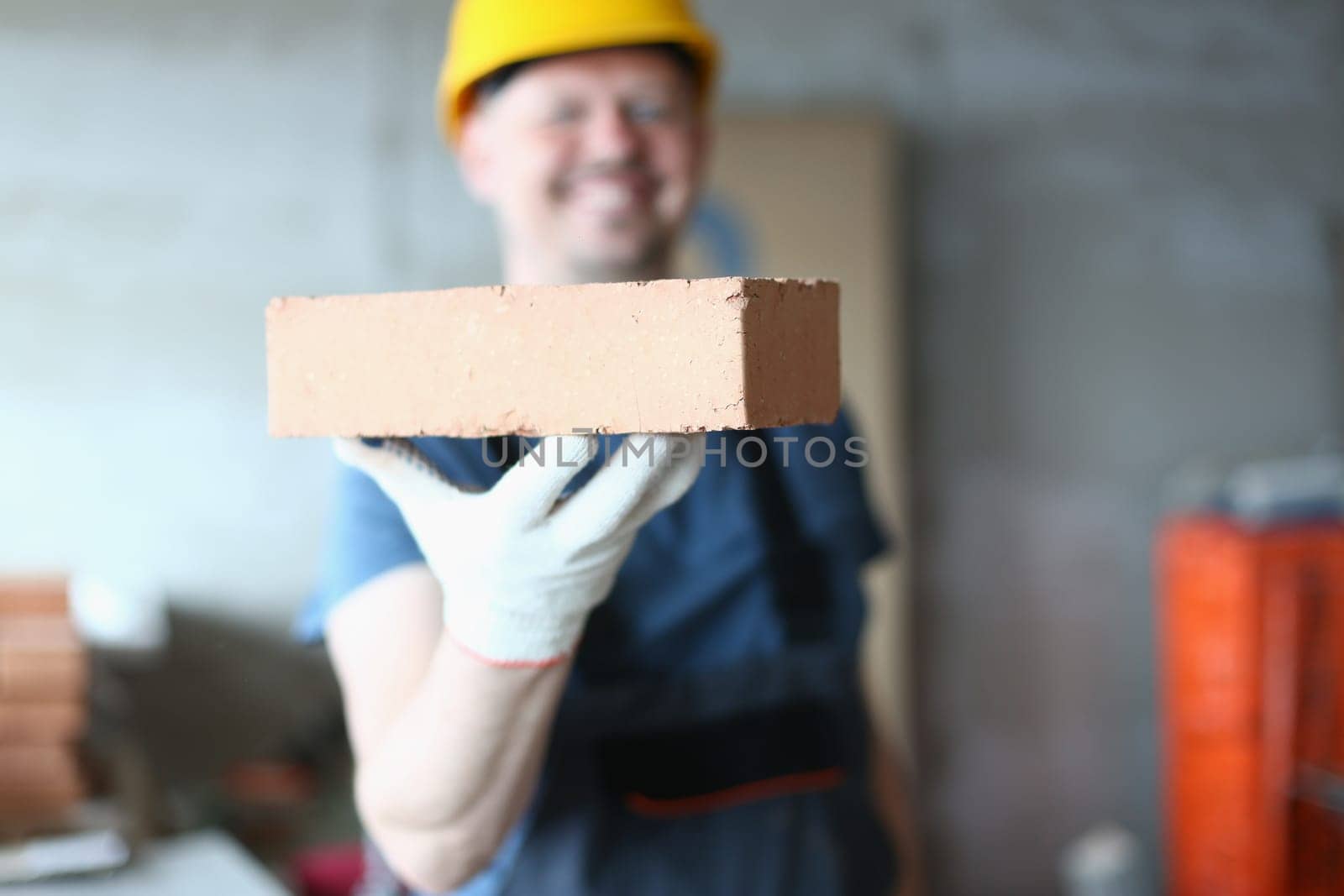 Master builder man holding red brick at construction site. Brick laying master concept