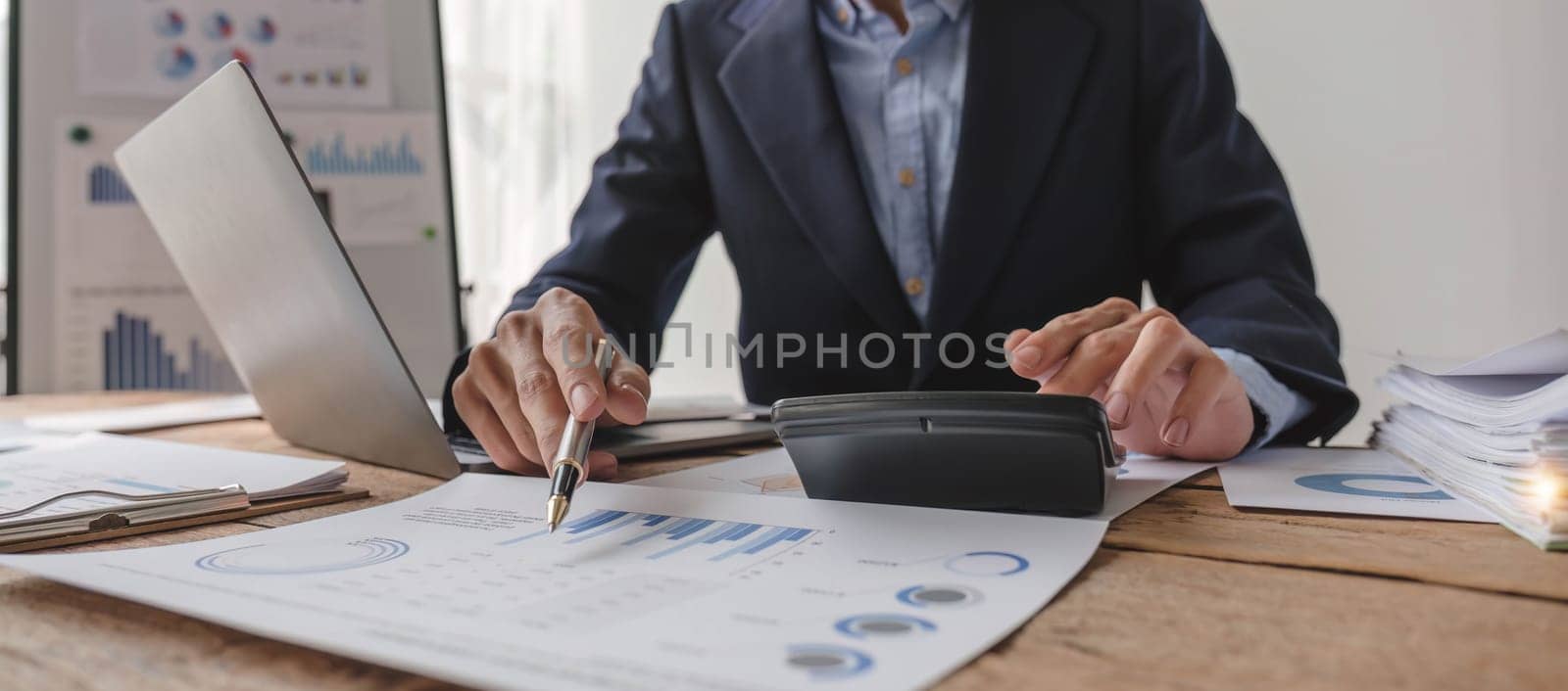 Close up Businessman using calculator and laptop for do math finance on wooden desk in office and business working background, tax, accounting, statistics and analytic research concept...