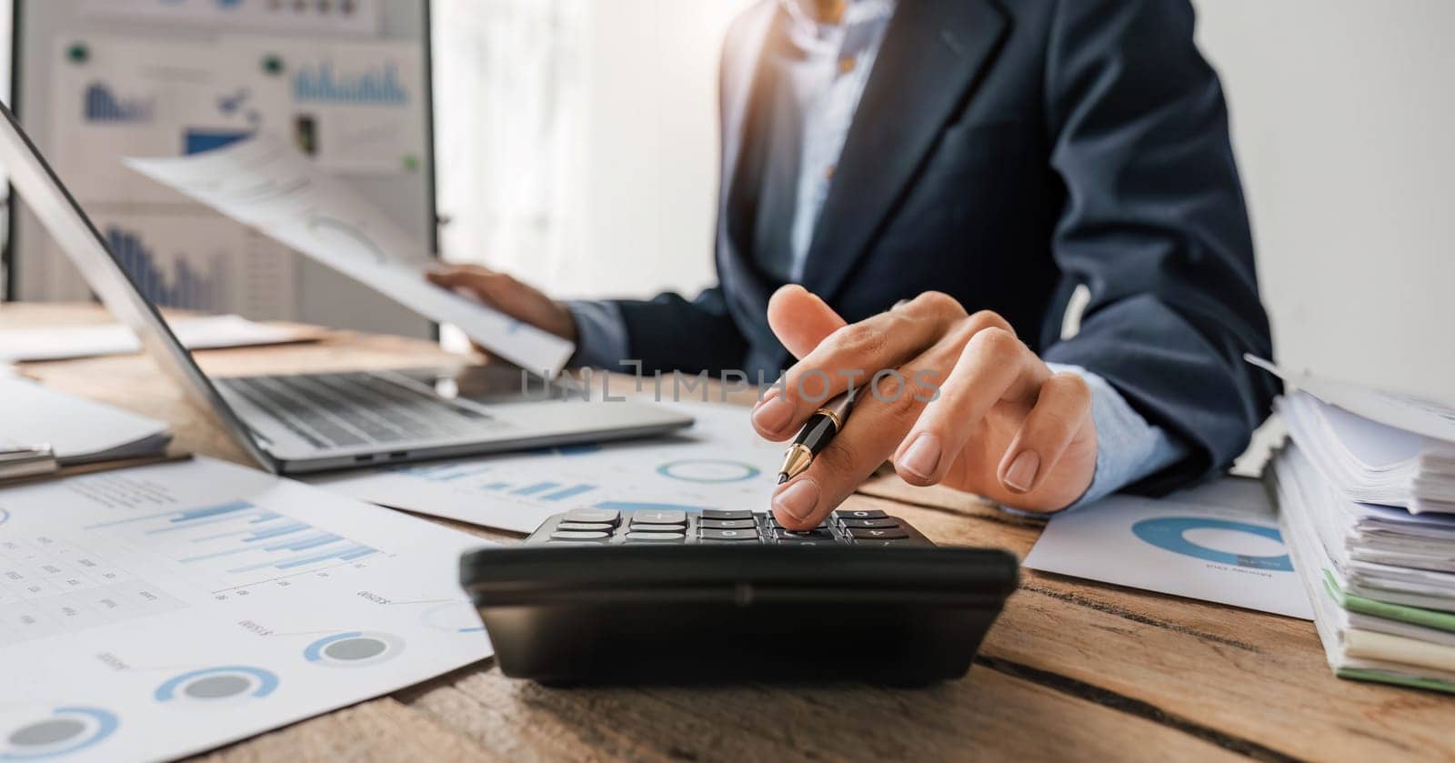 Close up Businessman using calculator and laptop for do math finance on wooden desk in office and business working background, tax, accounting, statistics and analytic research concept. by wichayada