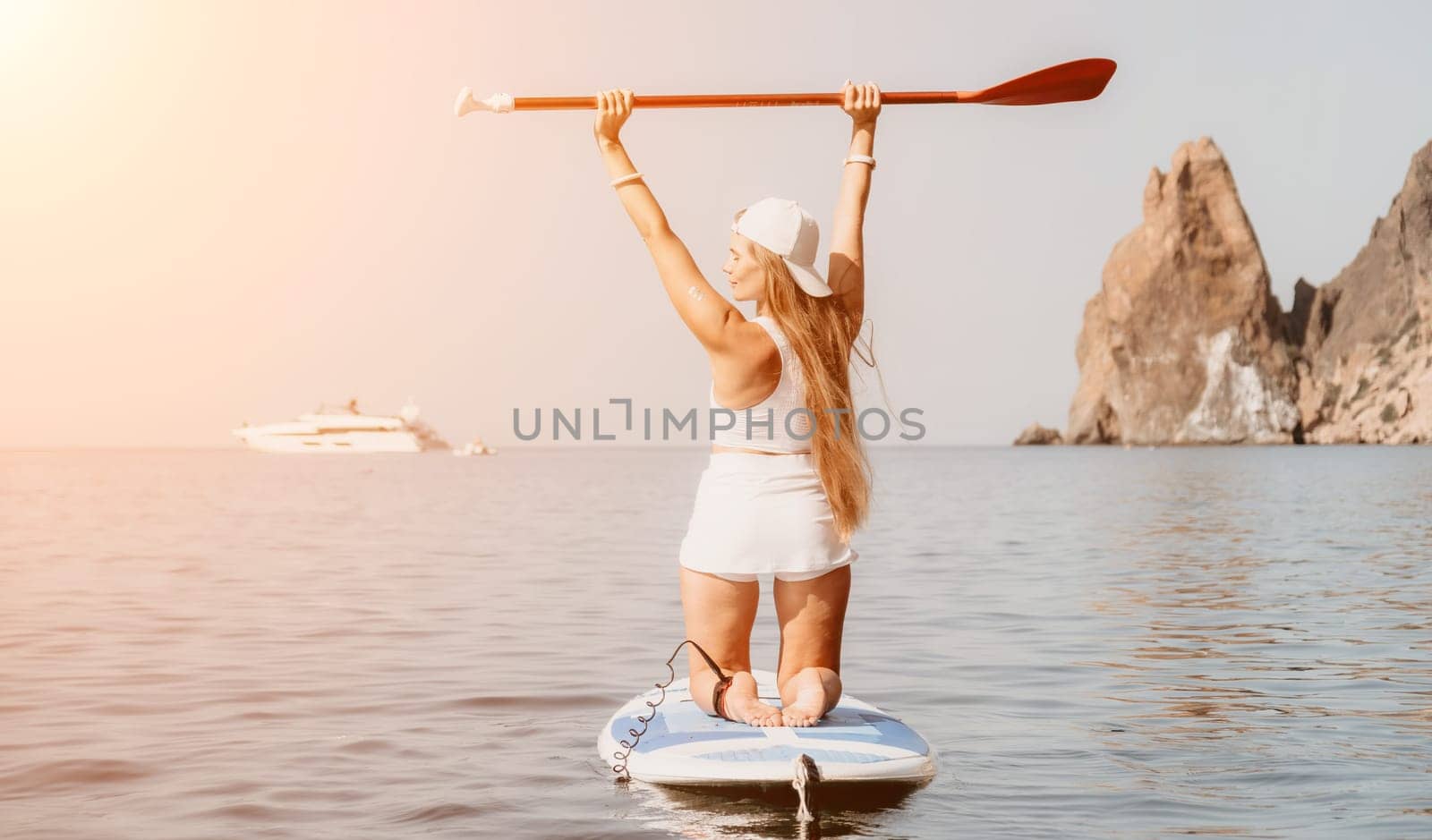 Woman sea sup. Close up portrait of happy young caucasian woman with long hair looking at camera and smiling. Cute woman portrait in bikini posing on sup board in the sea by panophotograph