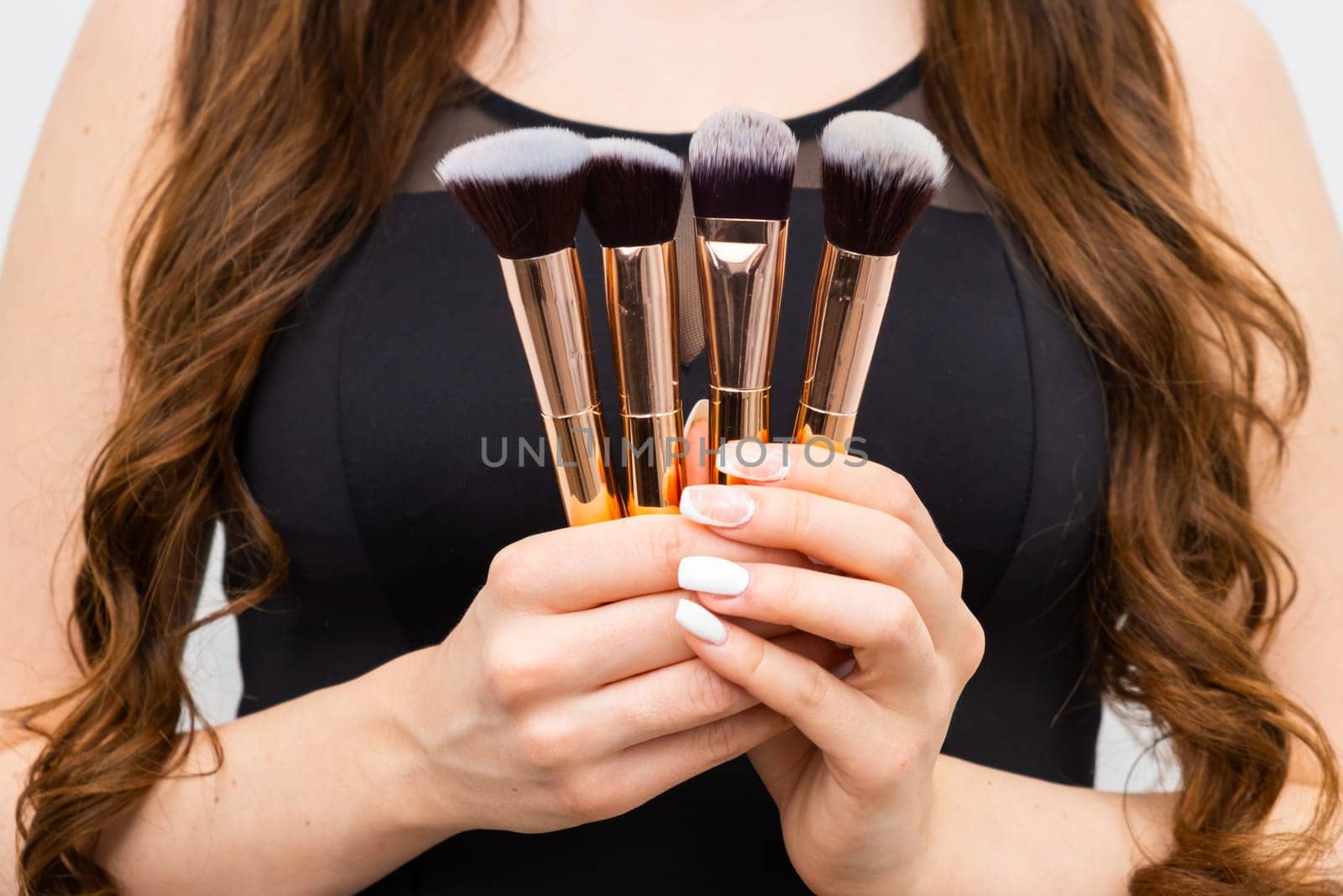 Close up in golden makeup brushes in woman hands with long hair by vladimka