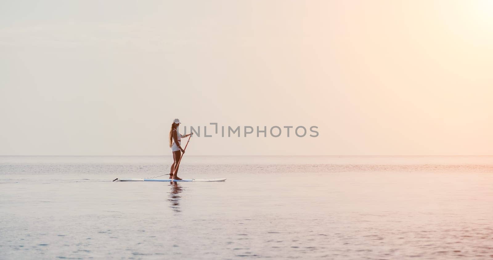 Close up shot of beautiful young caucasian woman with black hair and freckles looking at camera and smiling. Cute woman portrait in a pink bikini posing on a volcanic rock high above the sea