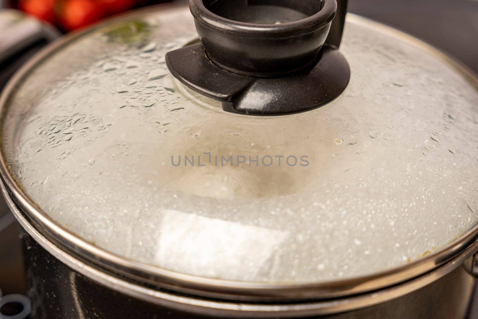 the misted lid of a pot of boiling water. Moist condensation from boiling water on the transparent glass lid of the kitchen pan while cooking on the stove