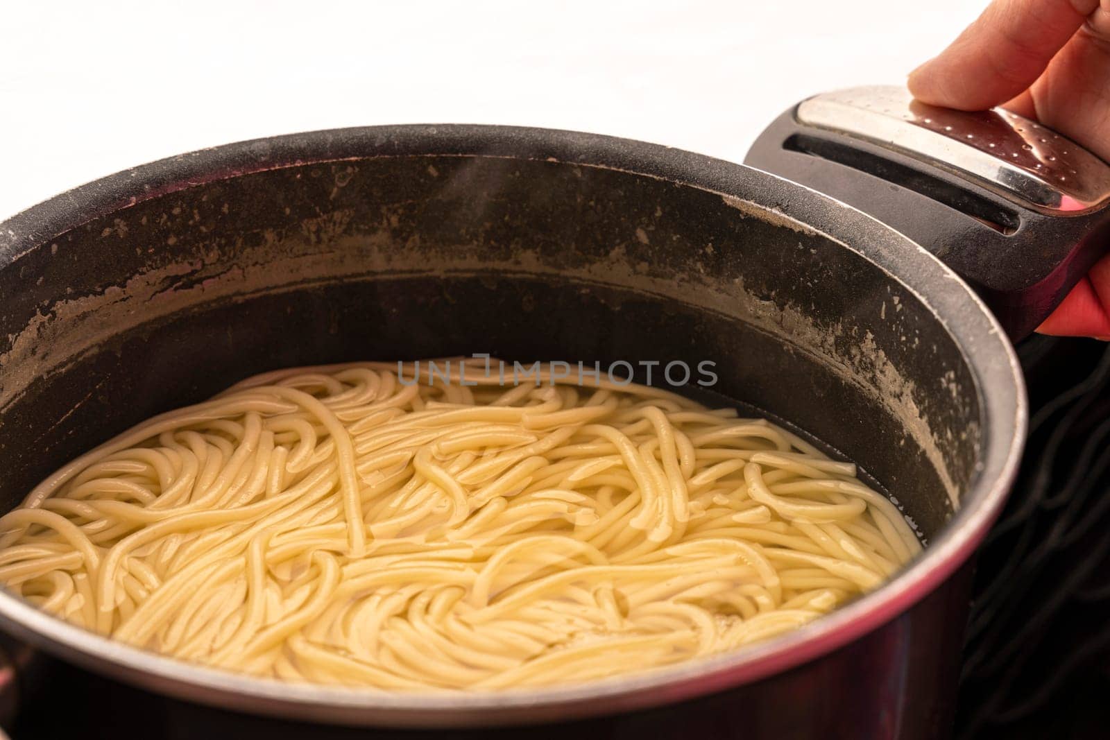 dinner at home. Simple vegetarian food. easy to cook. close-up of spaghetti in a saucepan in the hands of a cook.
