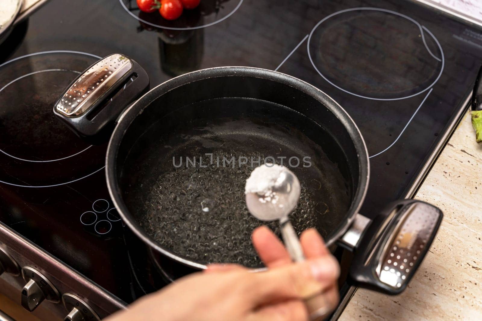 Putting salt in hot boiling water in pan. cooking a vegetarian dinner by audiznam2609