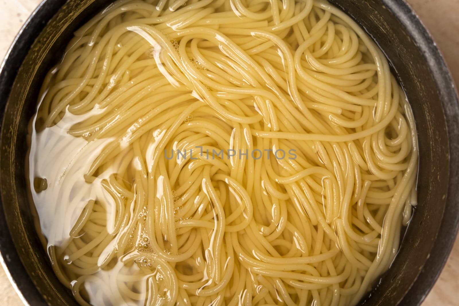 boiled spaghetti in water. Boiling spaghetti in pan on electric stove in the kitchen. Close-up of spaghetti pasta In hot water in kitchen pan. Preparation for making Spaghetti. Top view