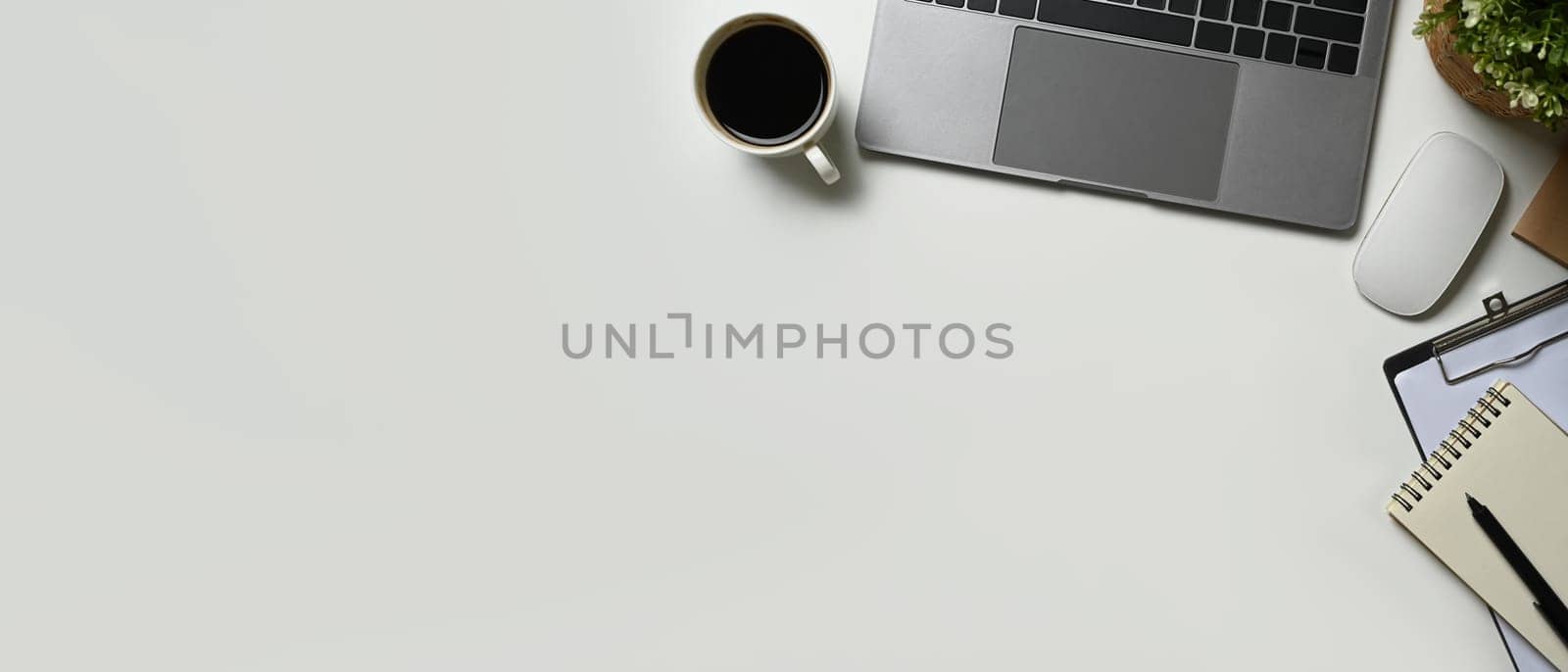 Flat lay, top view of white office desk with laptop computer, coffee cup and notebook. Copy space for advertise text by prathanchorruangsak