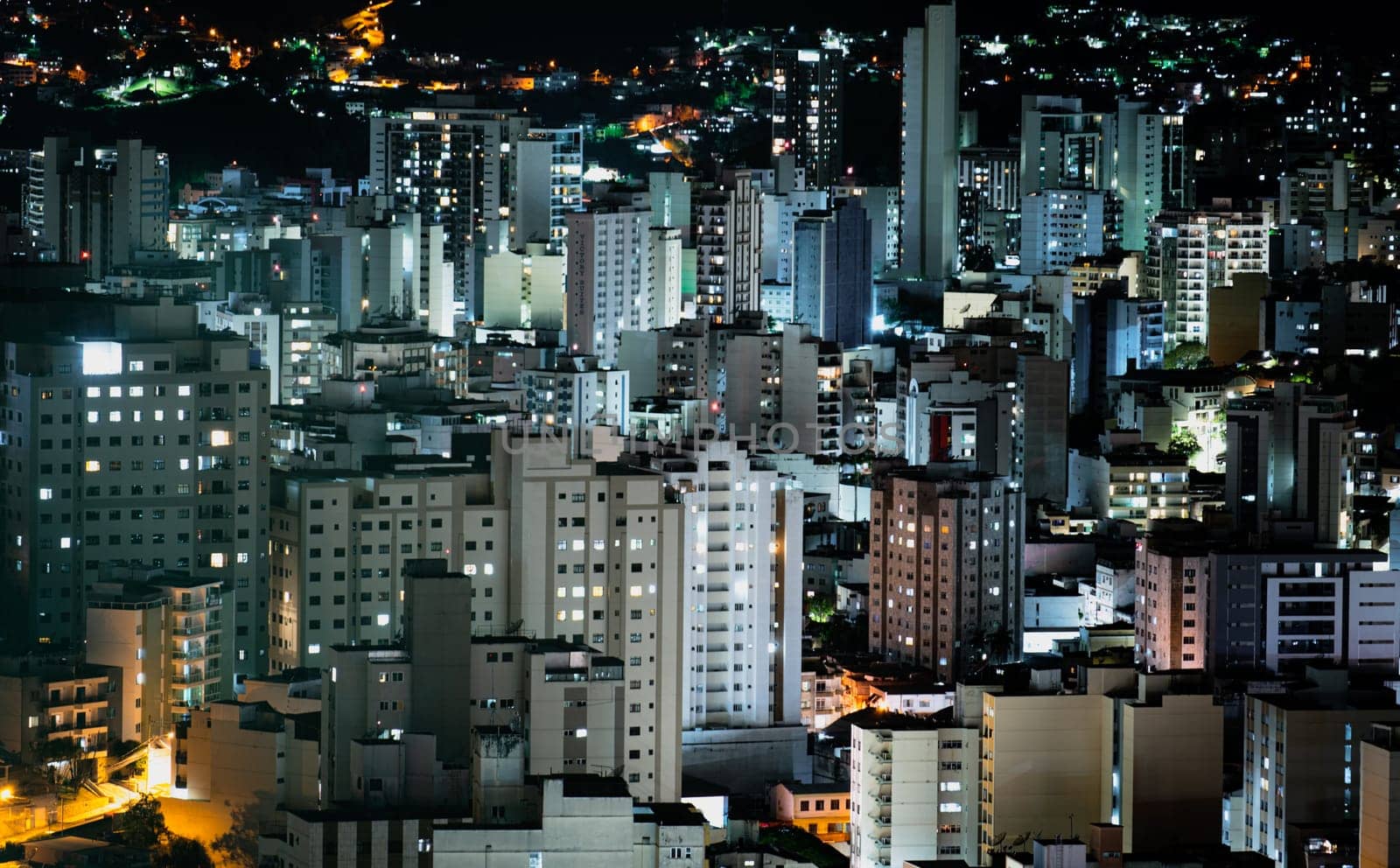 View of the city center with compressed skyscrapers, illuminated by lights at dusk.