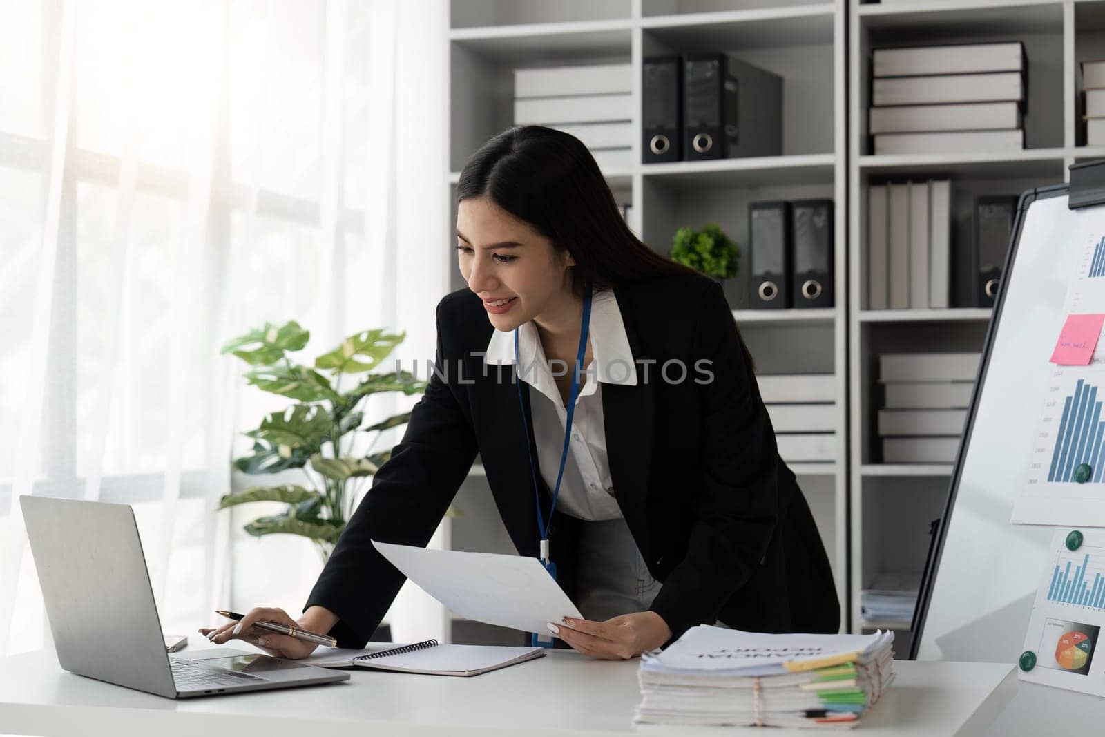 young business beautiful focused woman working with laptop and document while at table in office by nateemee