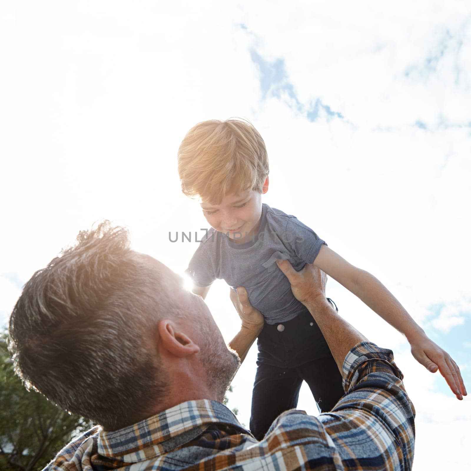 Raising him to incredible heights. a father lifting his son high into the air