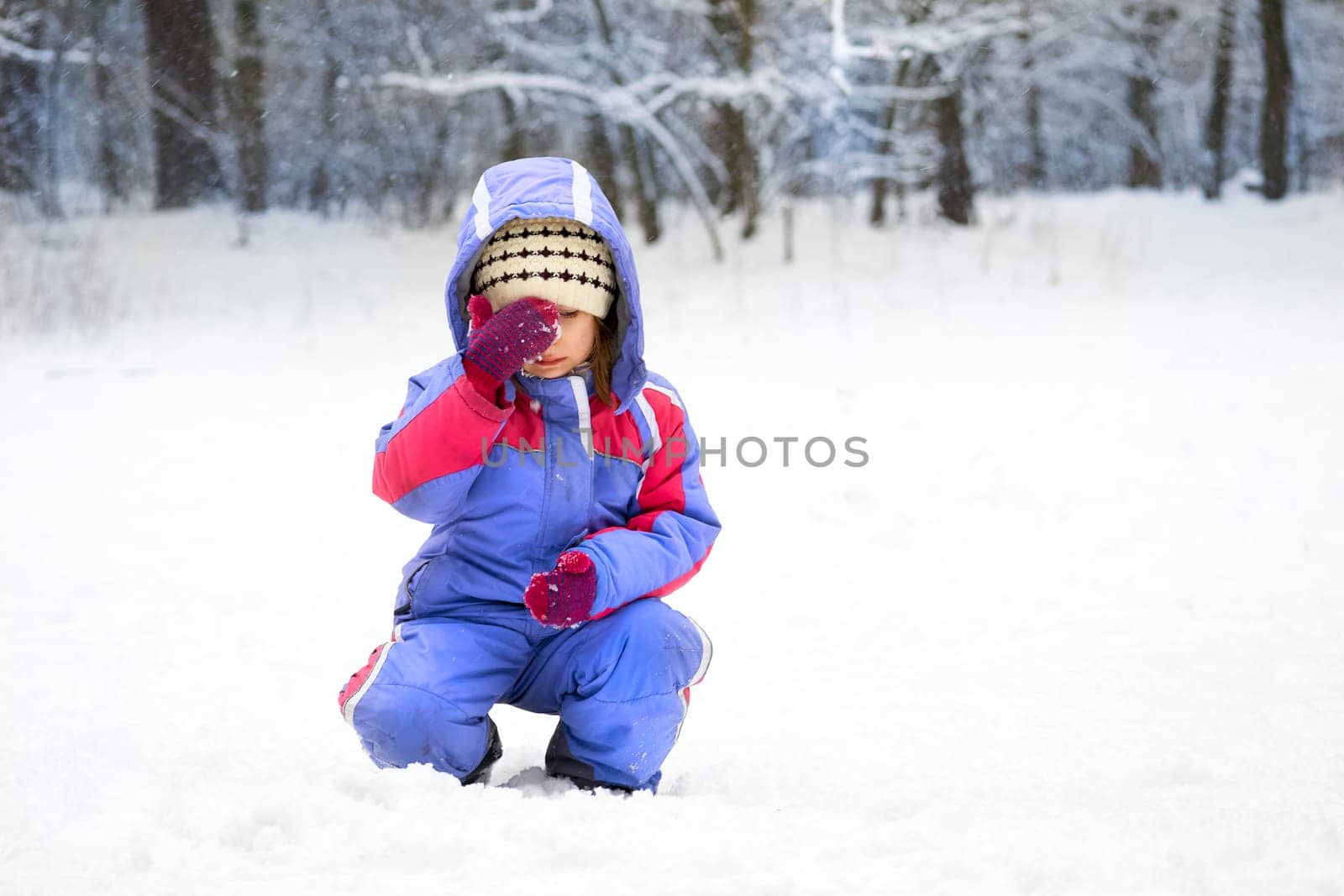 a young human being below the age of puberty or below the legal age of majority. Cute thoughtful sad child in a winter meadow in the forest.