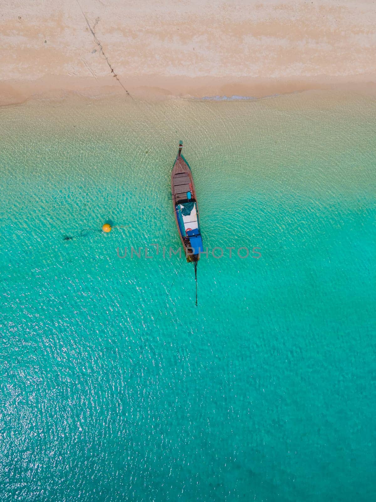 Koh Kradan Island with a white tropical beach and turqouse colored ocean. Drone aerial view at the beach with longtail boat