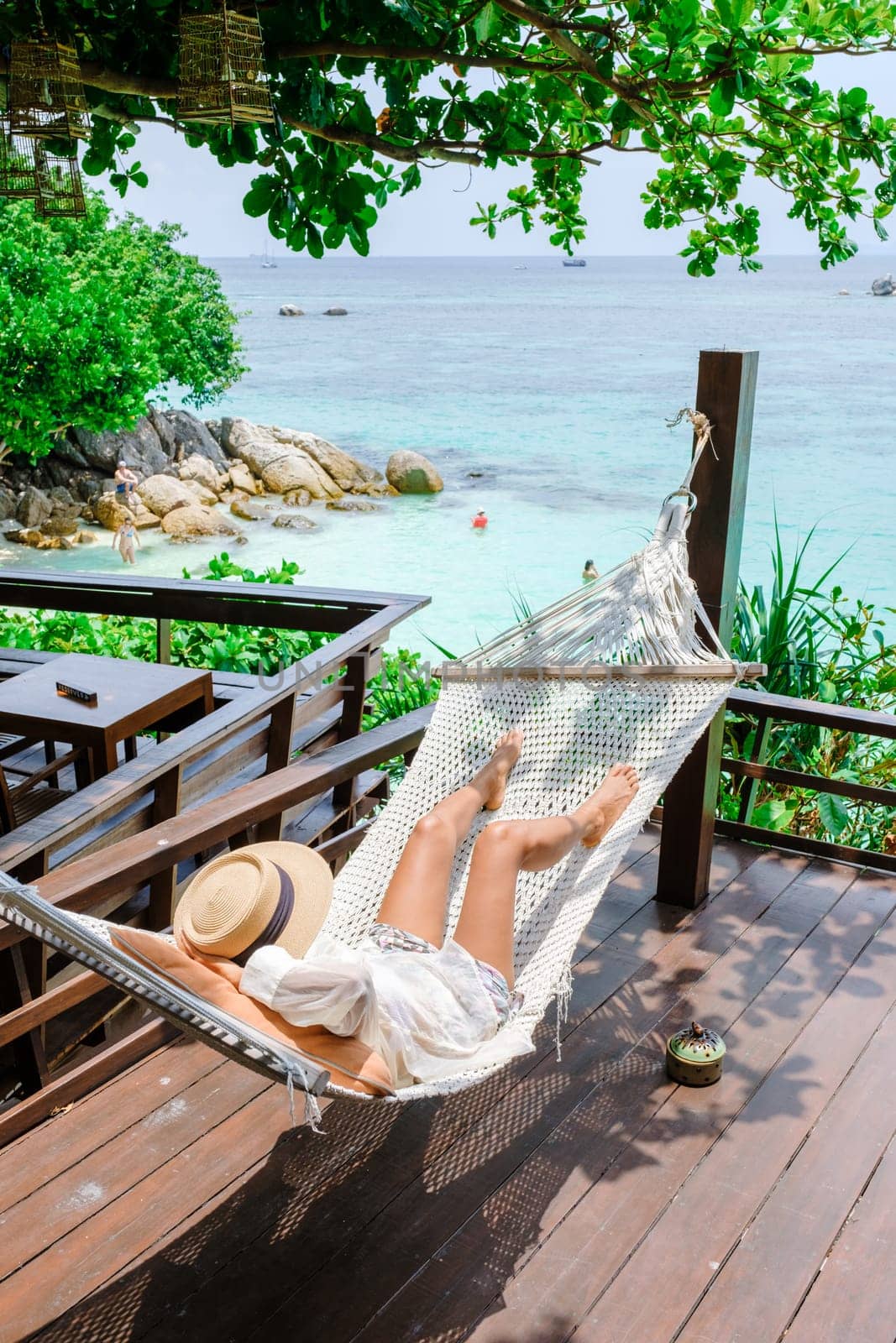 Asia women on vacation at Koh Lipe Island Thailand relaxing at a hammock, a tropical Island with a blue ocean and white soft sand. Ko Lipe Island Thailand