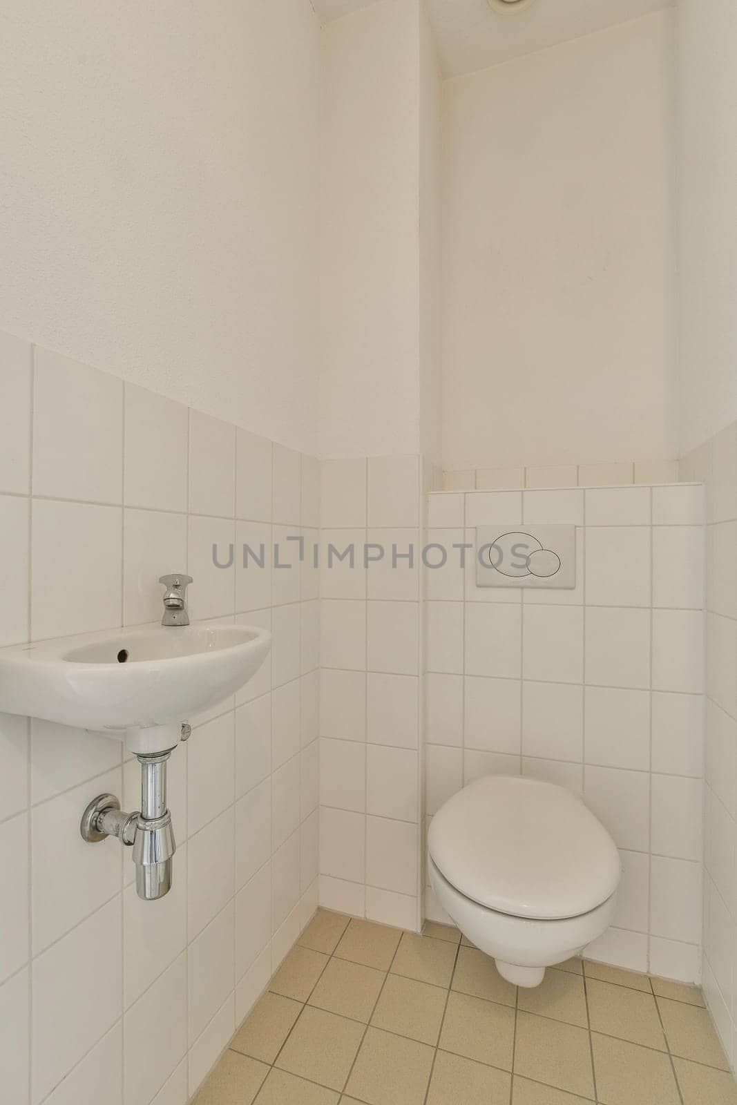 a bathroom with white tiles on the walls, and a toilet bowl in the corner next to the sink basin